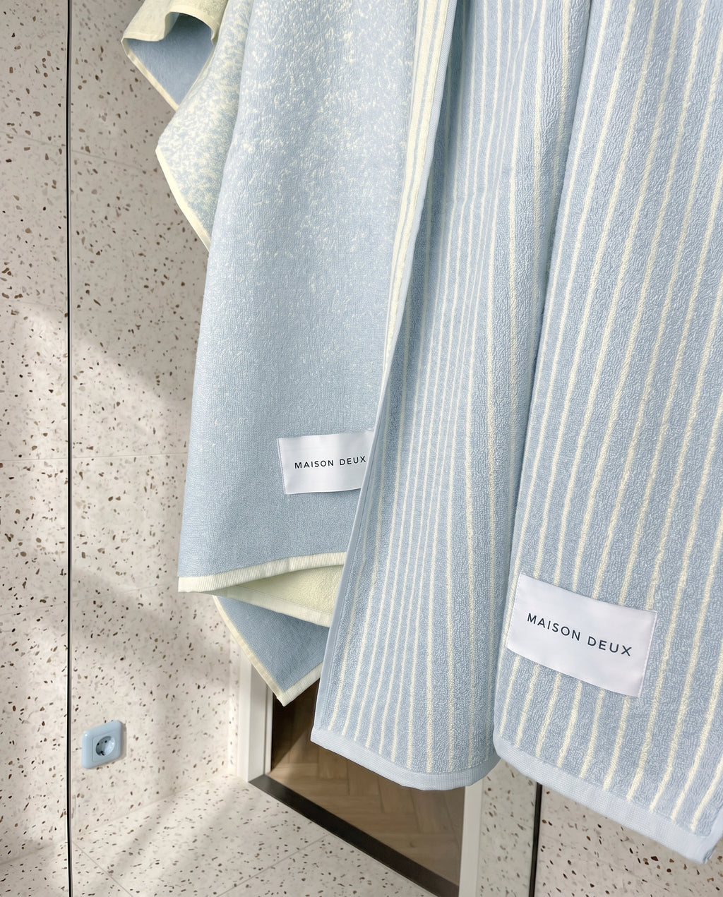 Blue and butter yellow gradient and striped towels hanging over shower glass door
