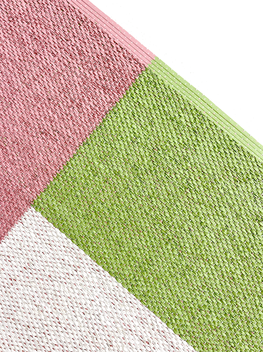 Close-up of corner of pink, green and cream color block vinyl doormat