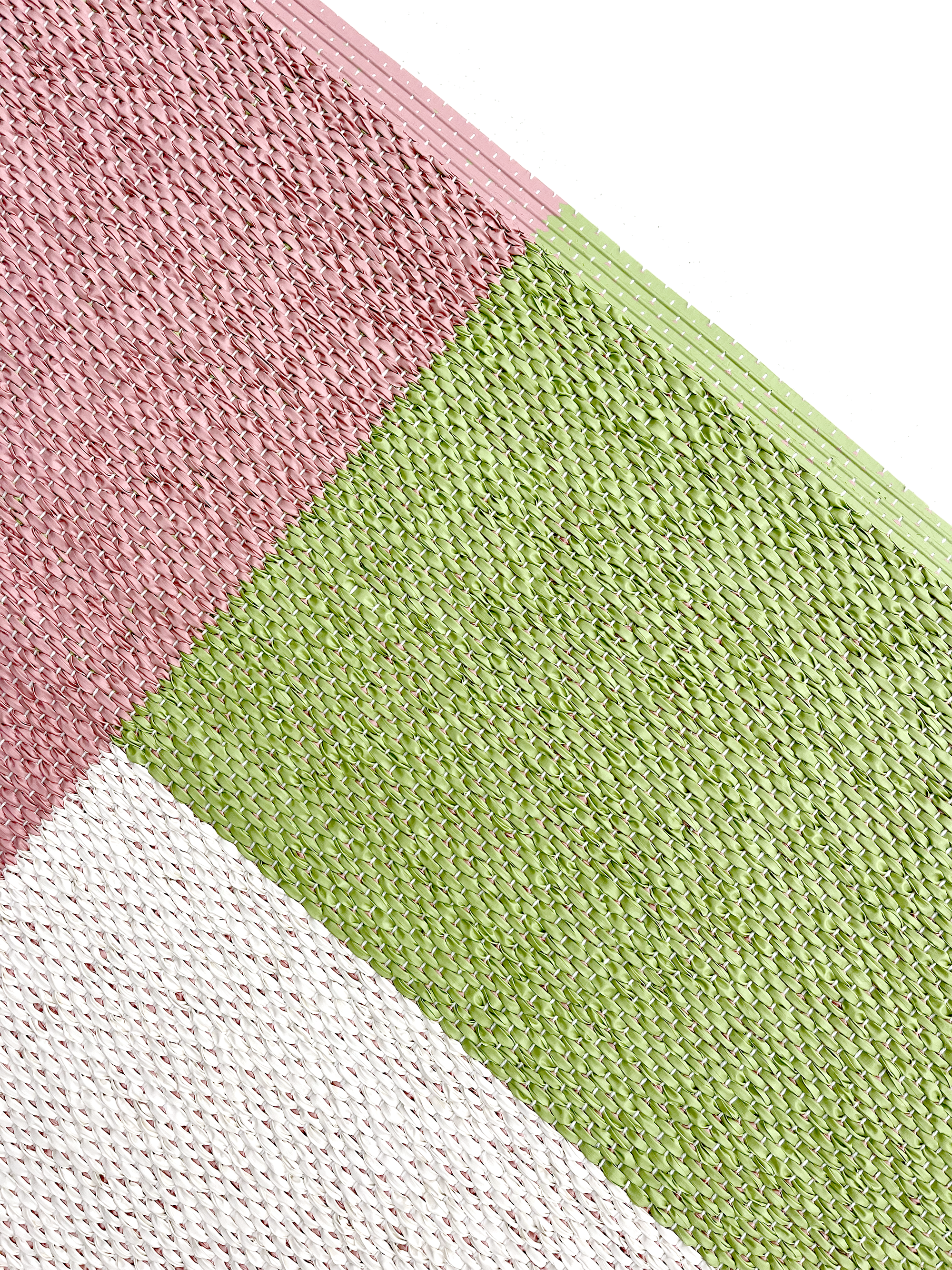 Close-up of corner of pink, green and cream color block vinyl doormat