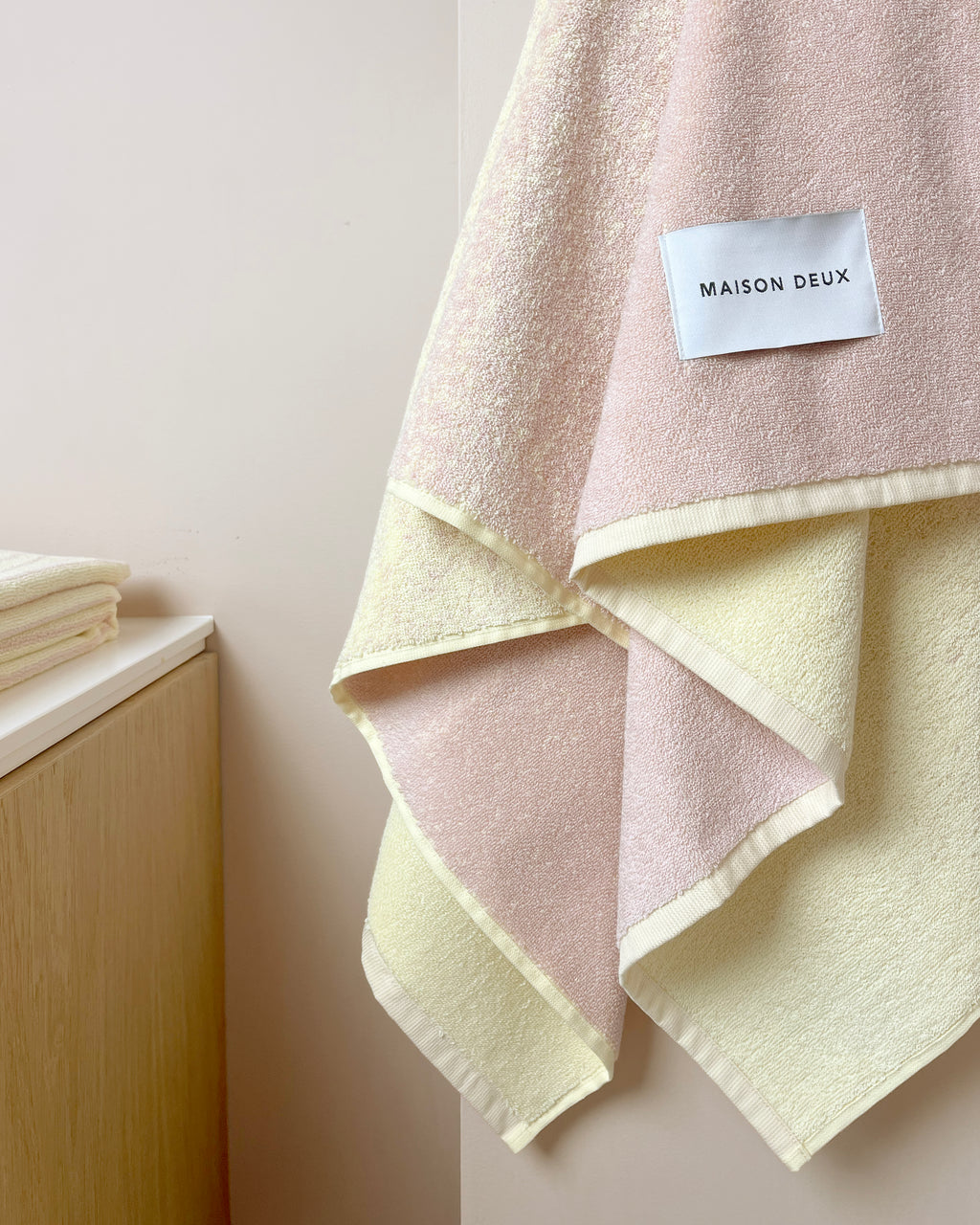 Butter yellow to pink gradient towel hanging near wooden cabinet