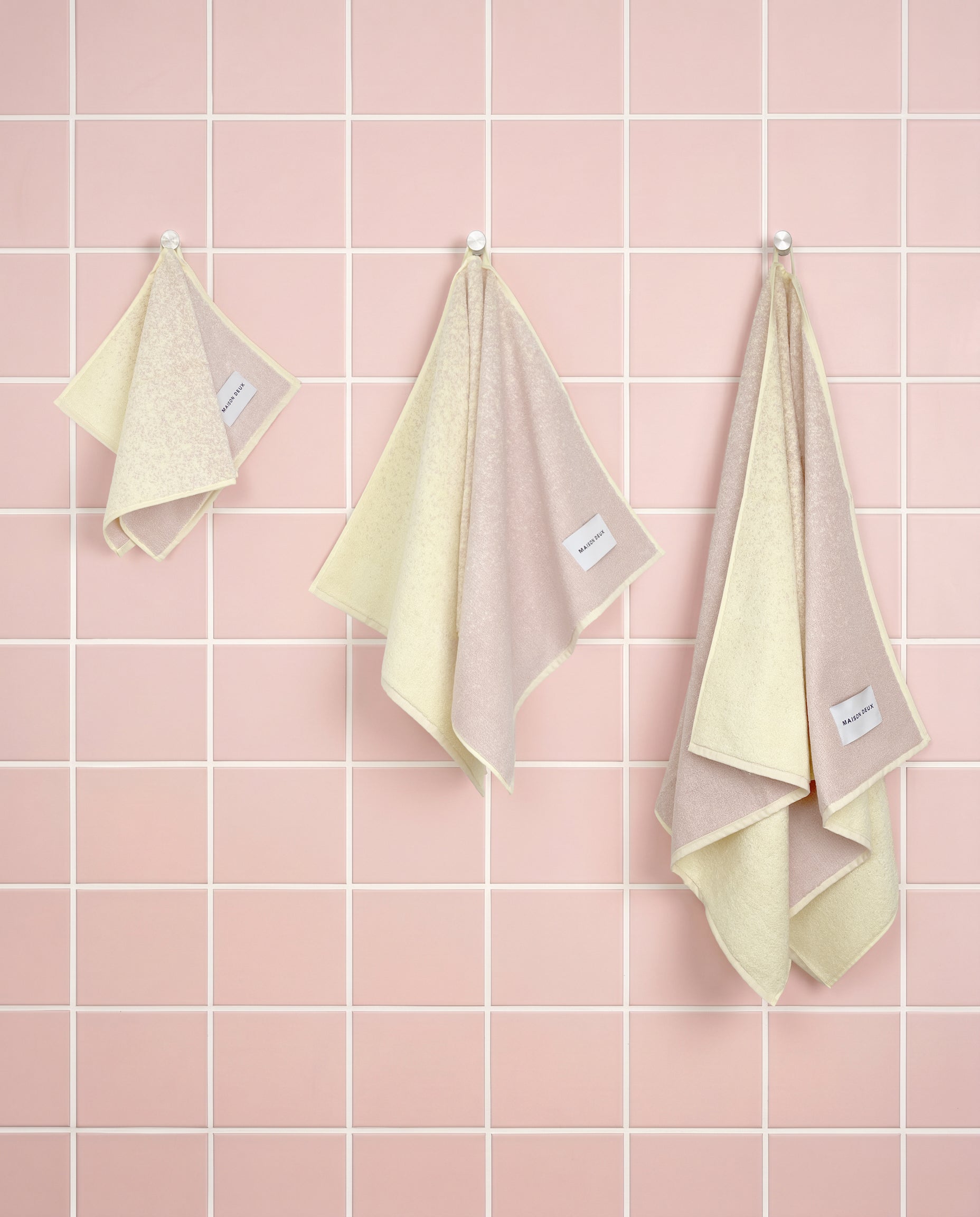 Butter yellow to pink gradient organic cotton towels shown in guest, hand and bath sizes