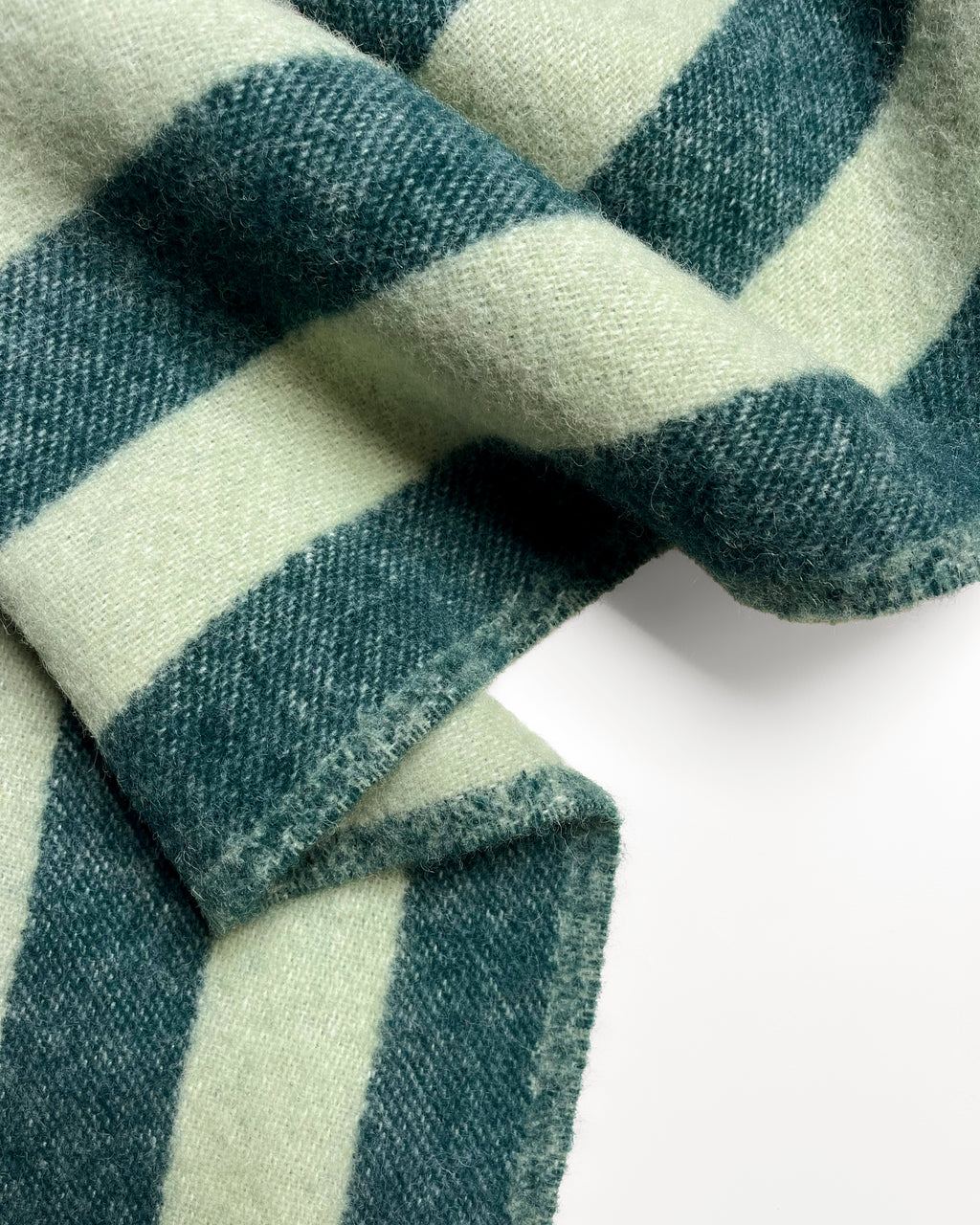 Close-up of folded dark green and sage striped wool blanket
