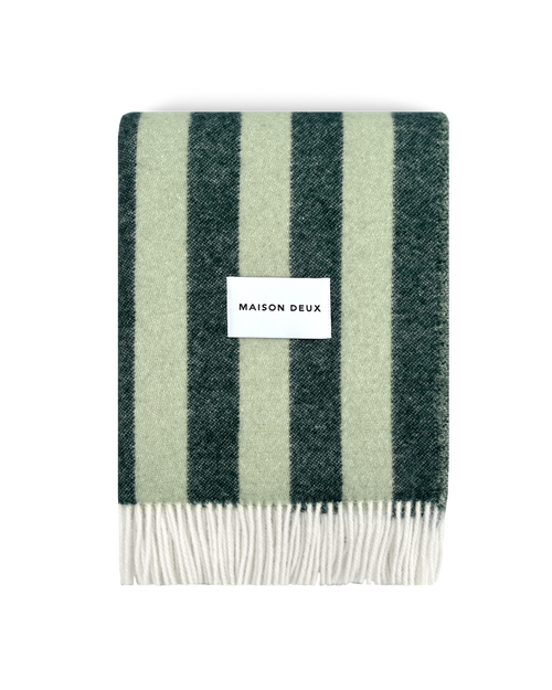 Dark green and sage striped wool blanket folded with fringe detail
