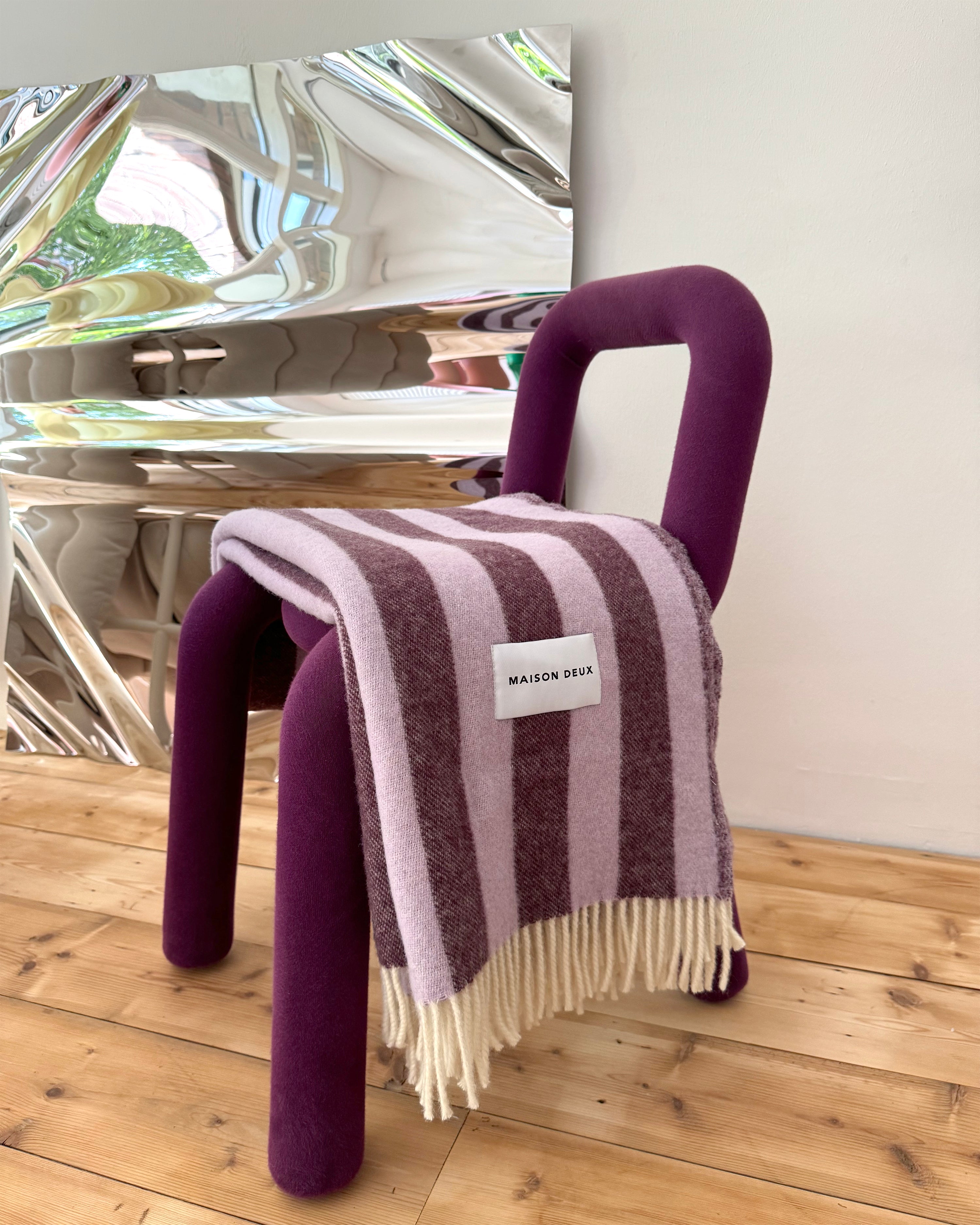 Lilac and aubergine striped wool blanket draped over chair
