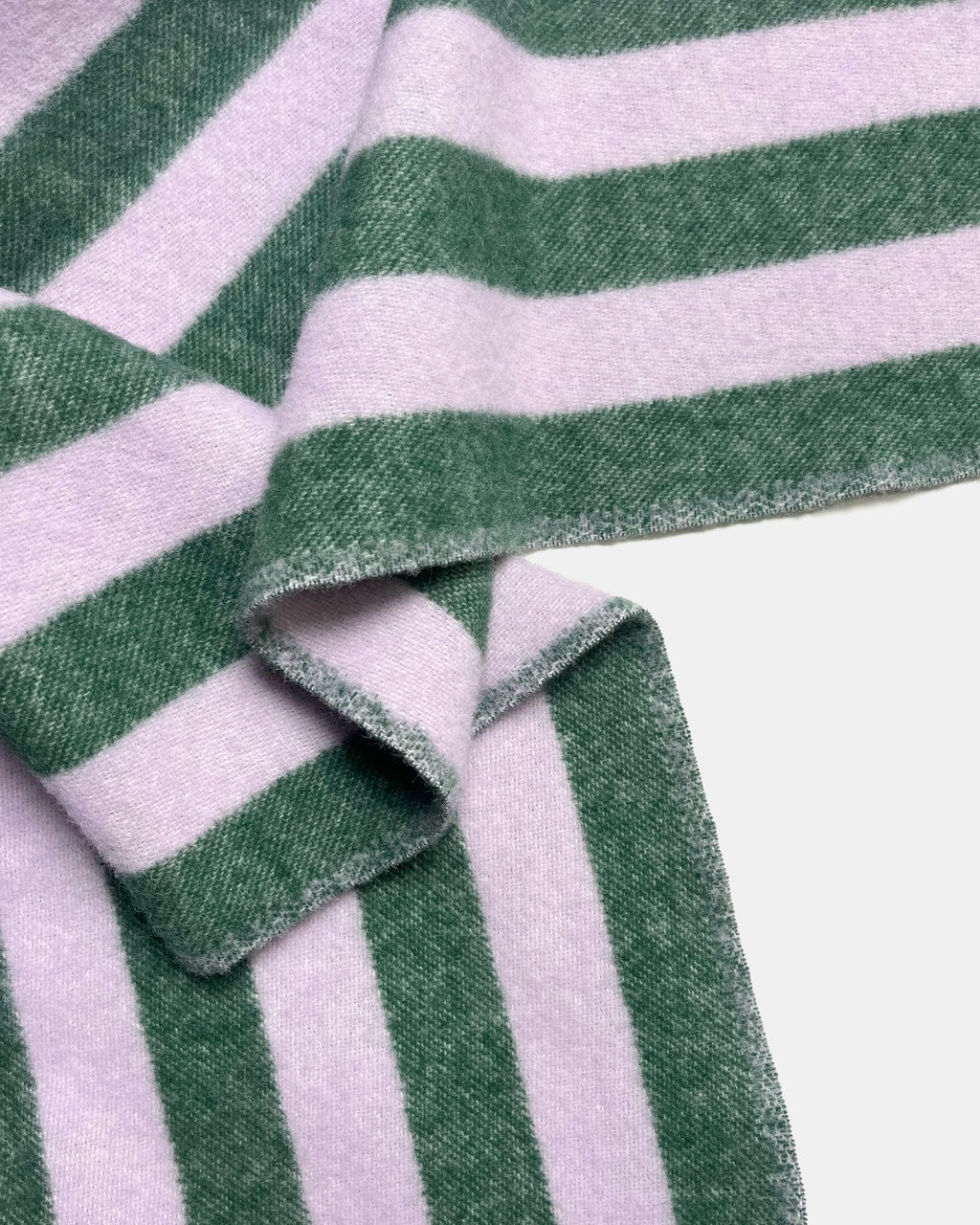 Close-up of folded lilac and green striped wool blanket

