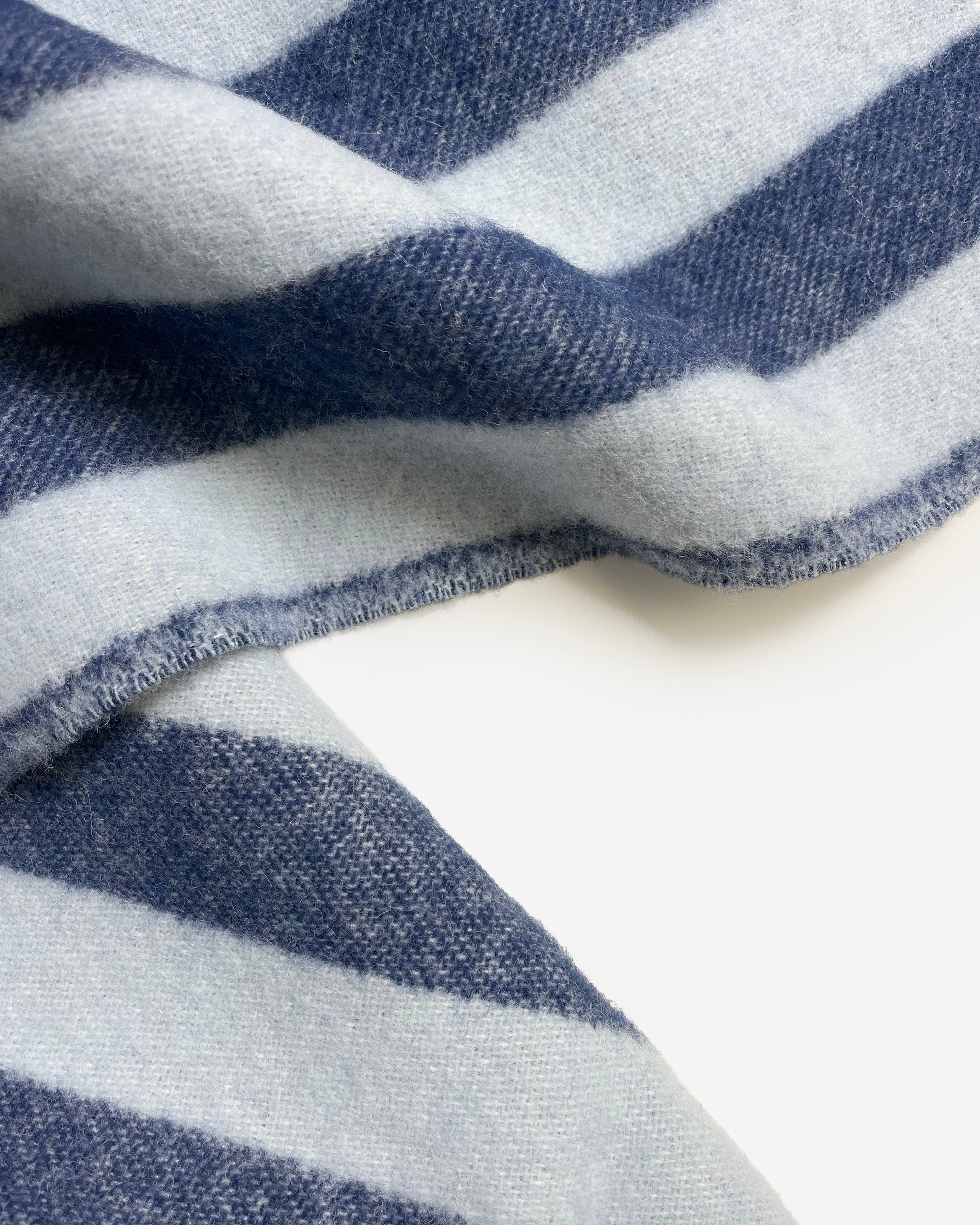 Close-up of folded navy and light blue striped wool blanket
