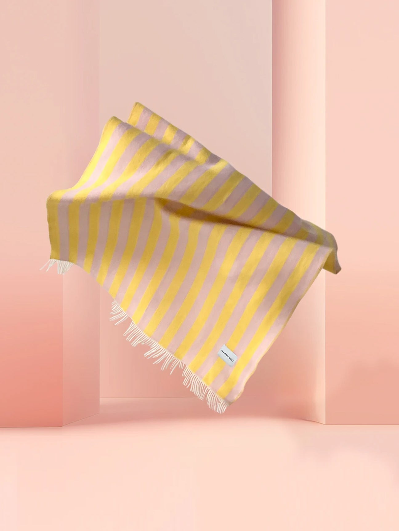 Pink and yellow striped wool blanket styled with pastel backdrop
