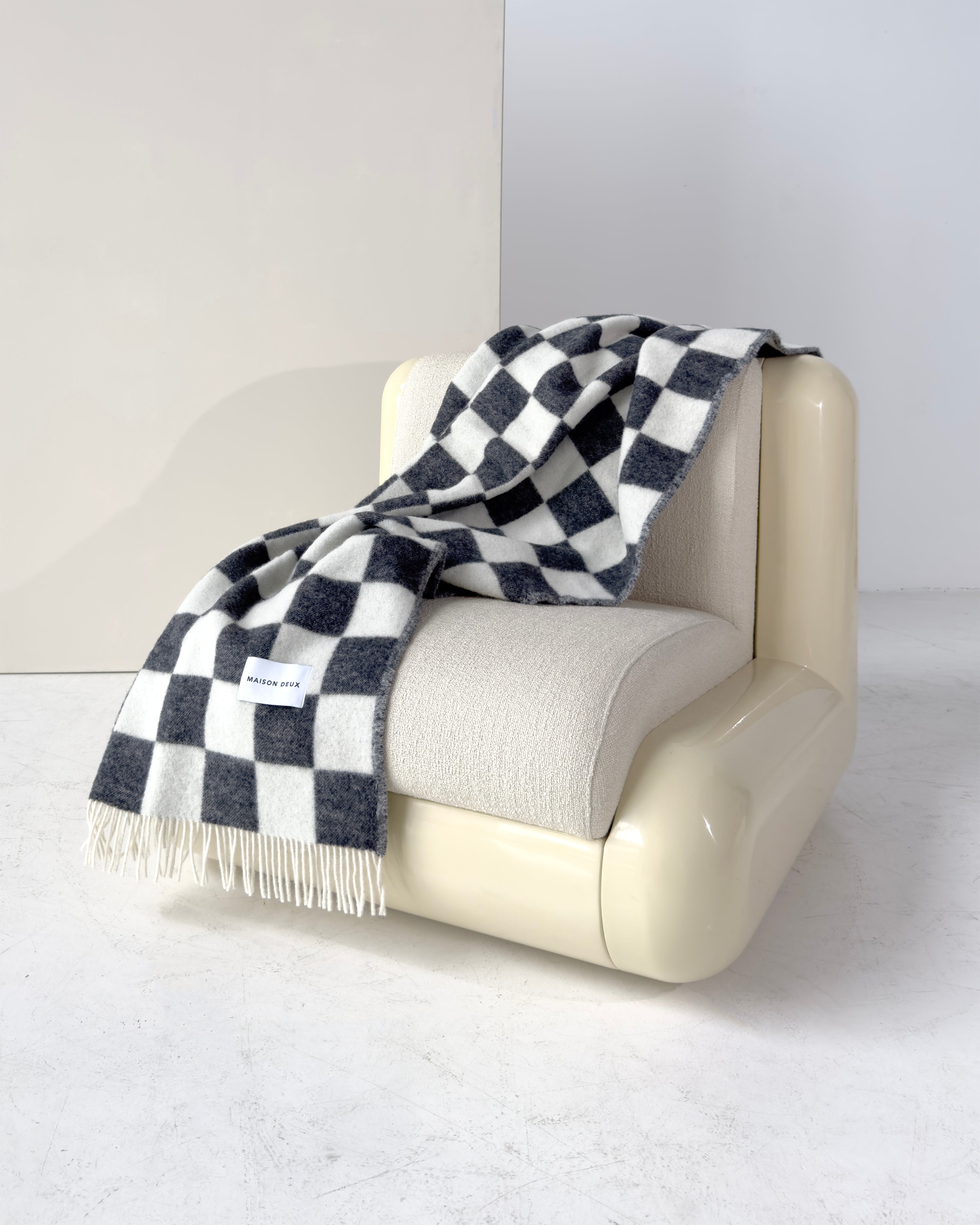 Black and white checkerboard wool throw draped over armchair
