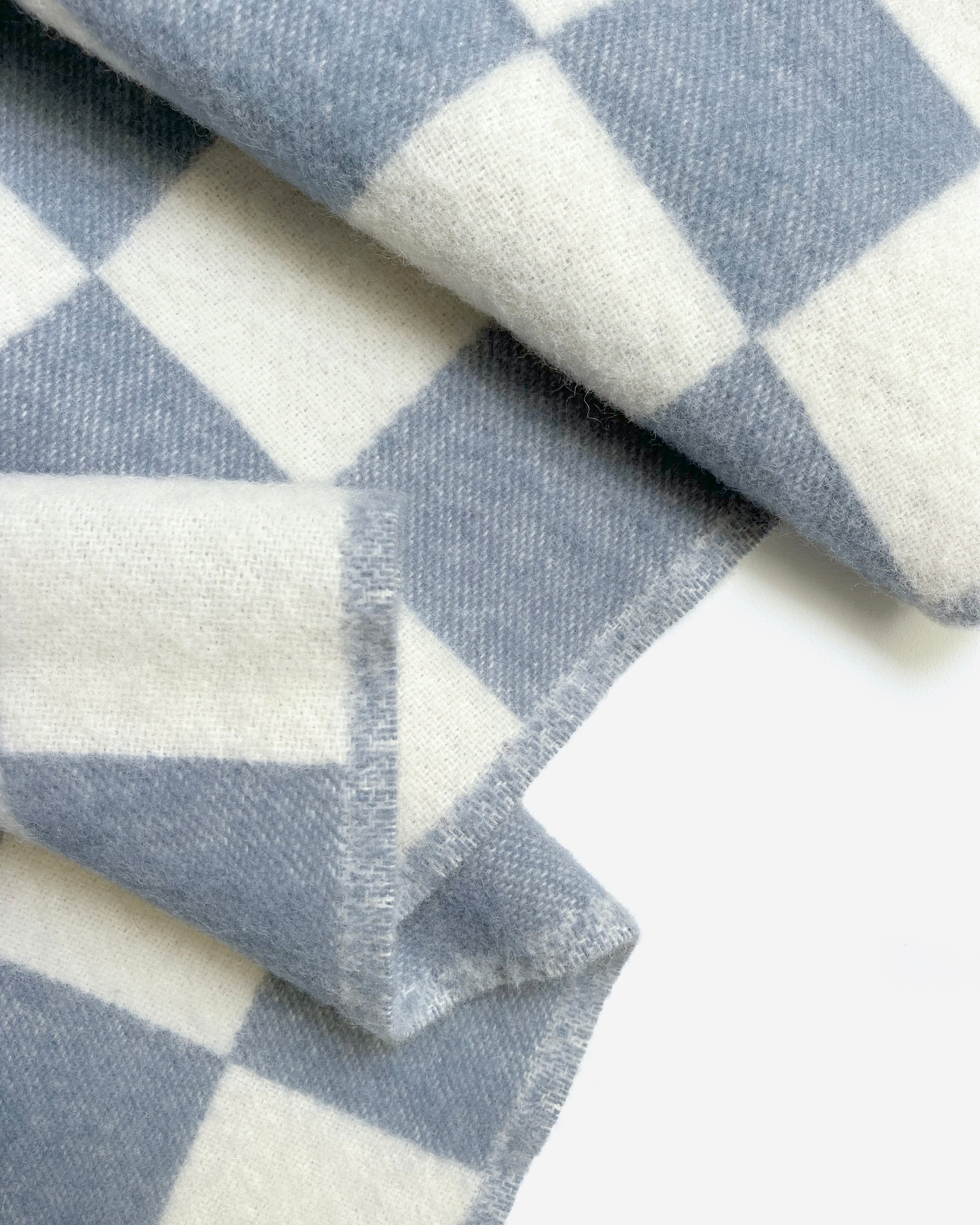 Close-up of folded denim blue and white checkerboard wool blanket

