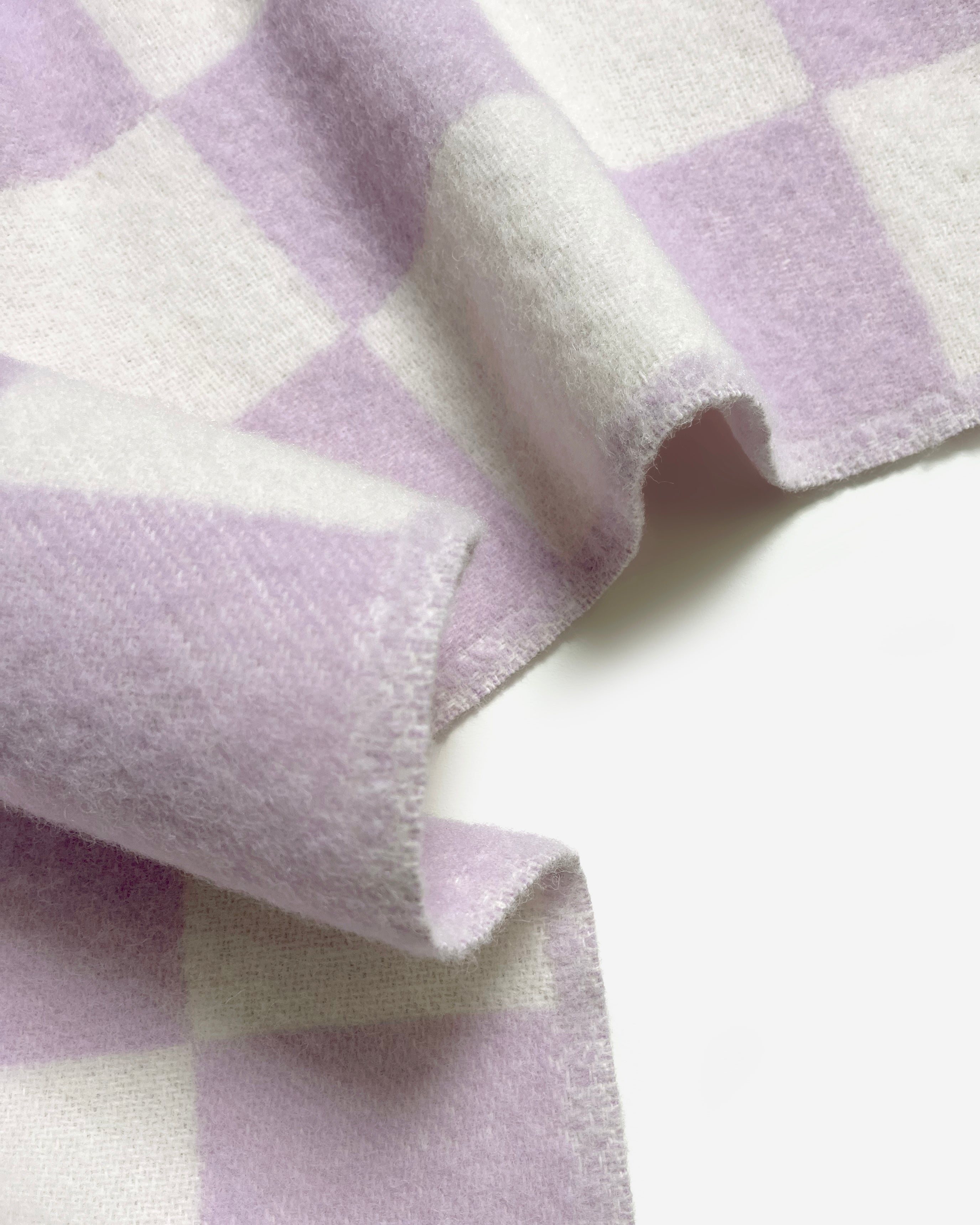 Close-up of folded lilac and white checkerboard wool blanket
