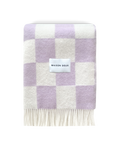 Lilac and white checkerboard wool blanket folded with fringe detail
