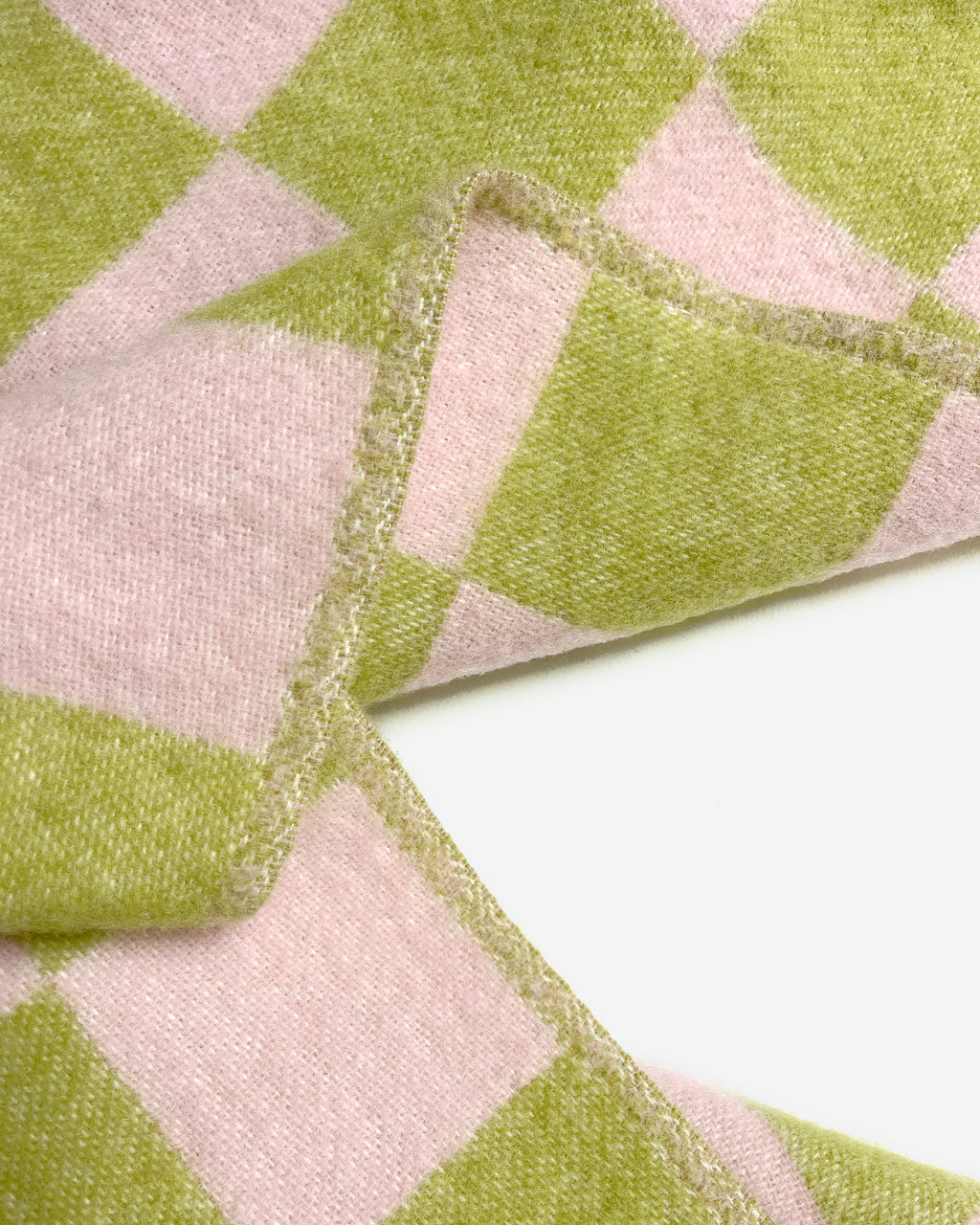 Close-up of folded lime green and pink checkerboard wool blanket
