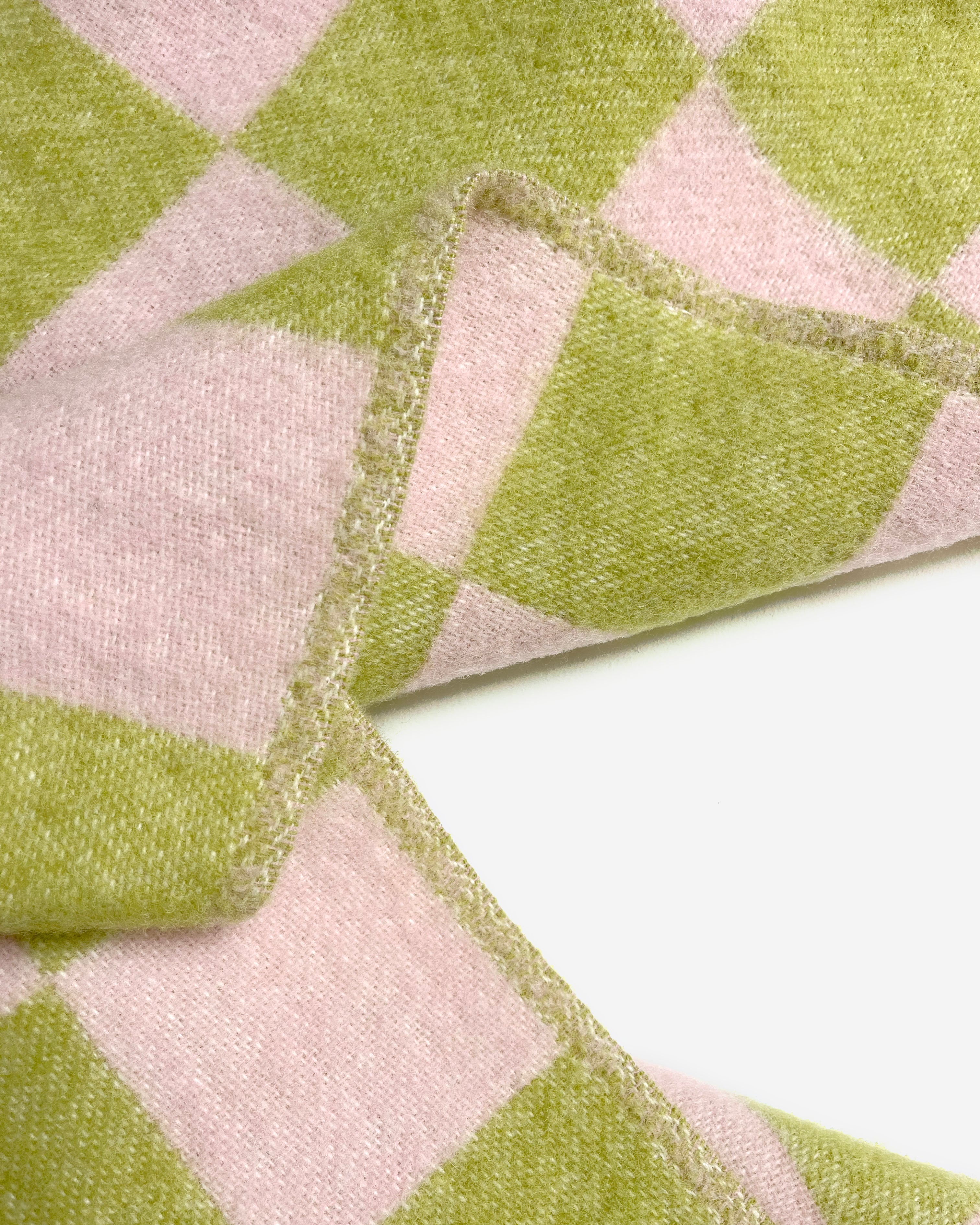 Close-up of folded lime green and pink checkerboard wool blanket
