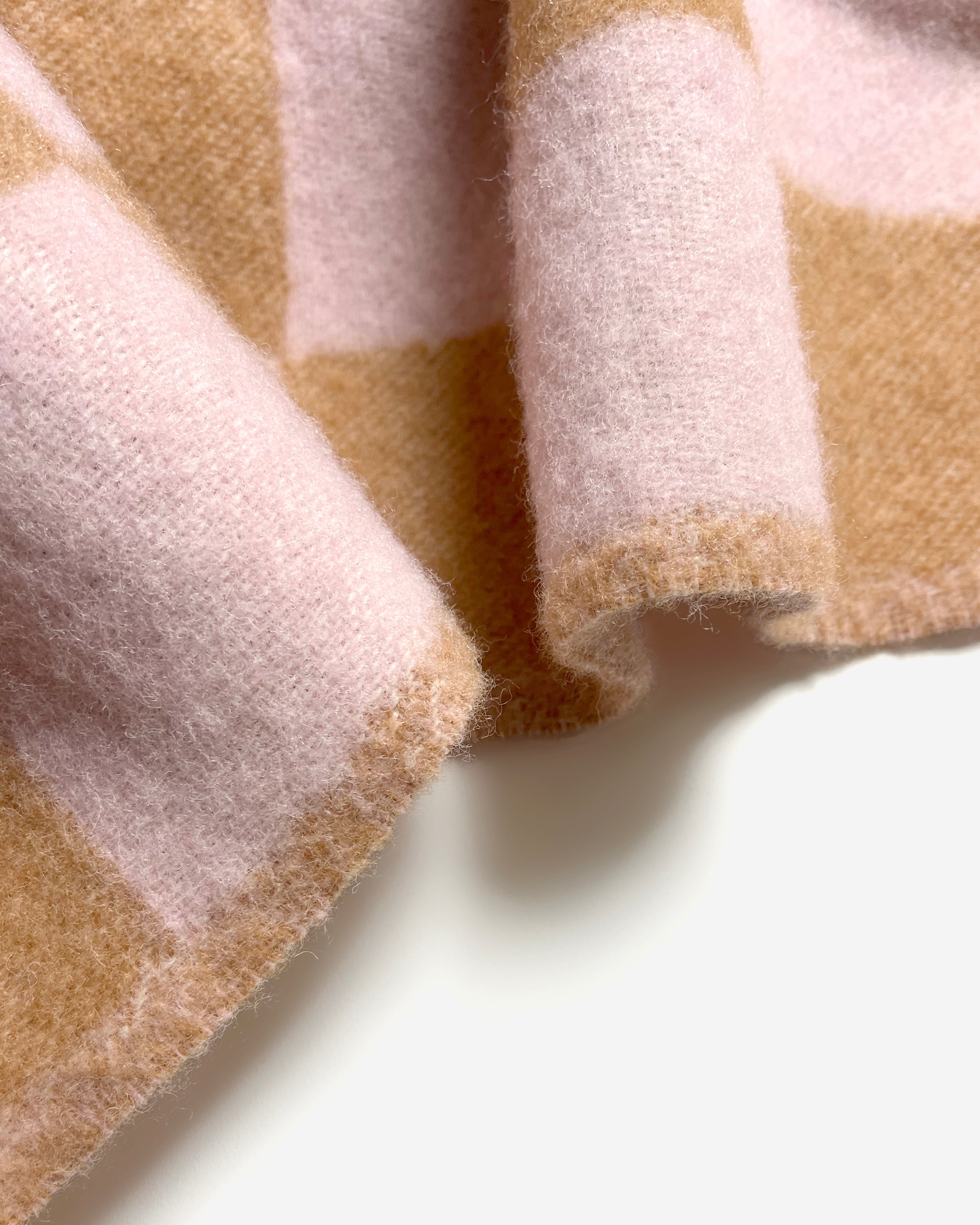Close-up of rolled terracotta and pink checkerboard wool blanket
