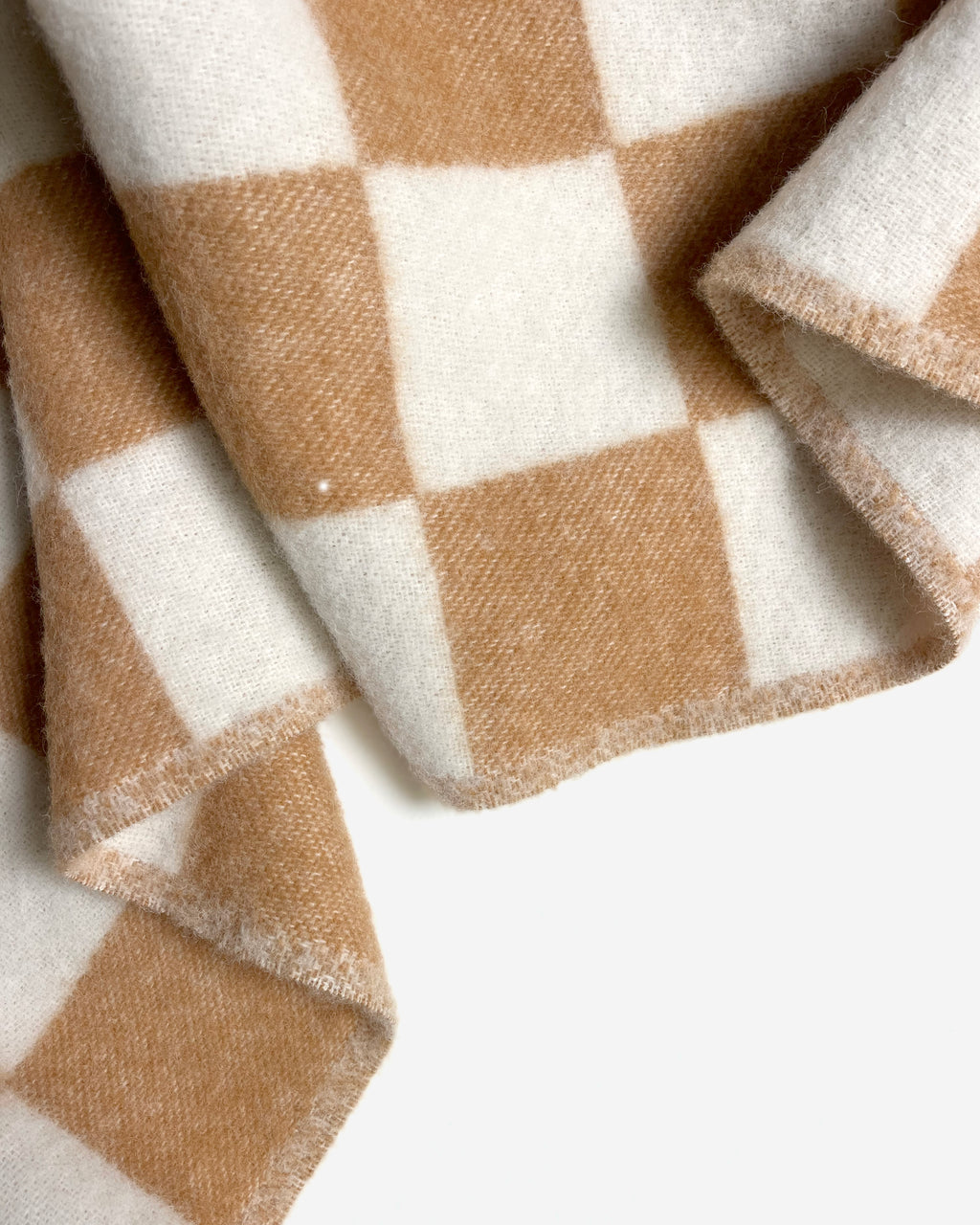 Close-up of folded terracotta and white checkerboard wool blanket
