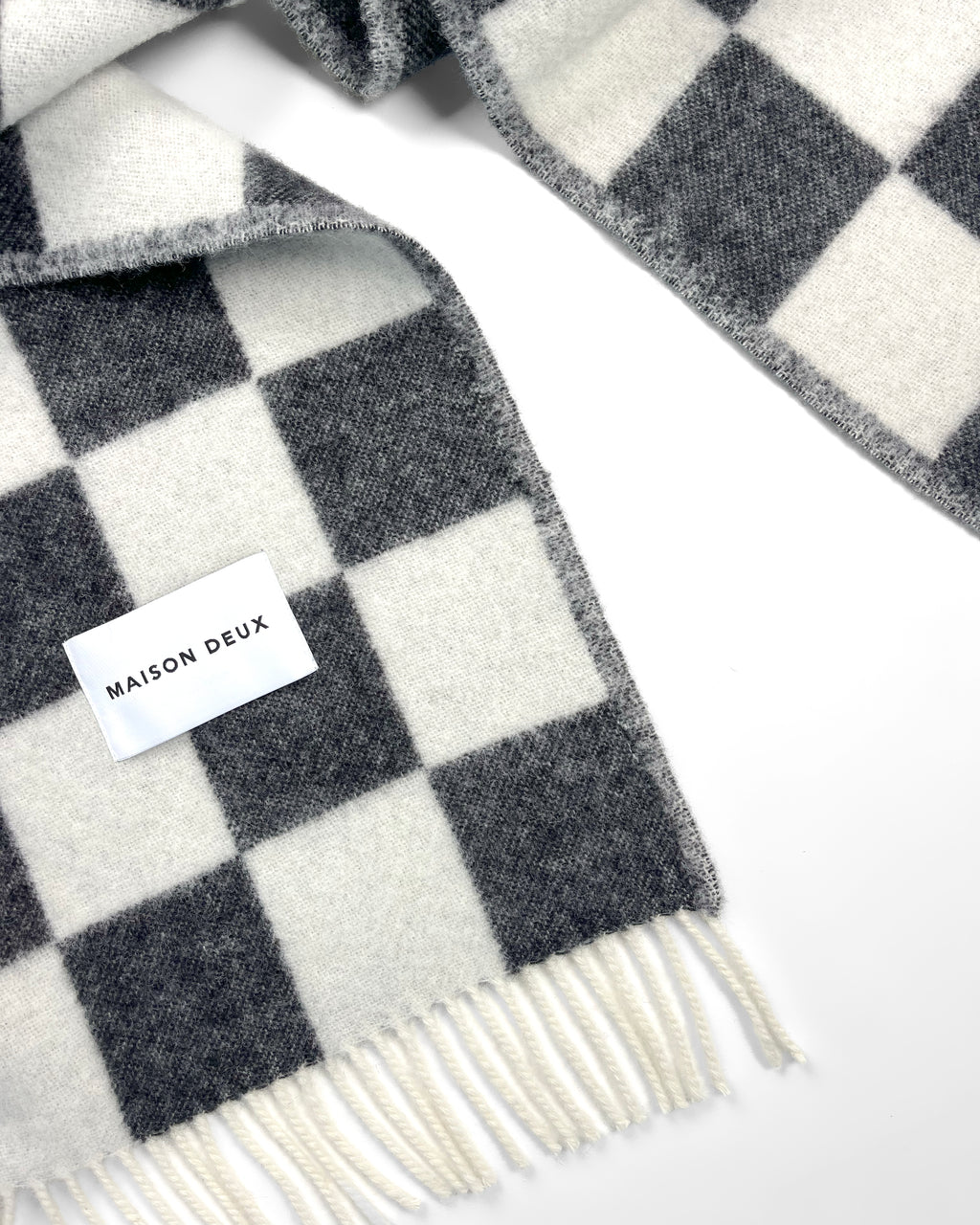Close-up of twisted black and white checkerboard wool plaid with fringe
