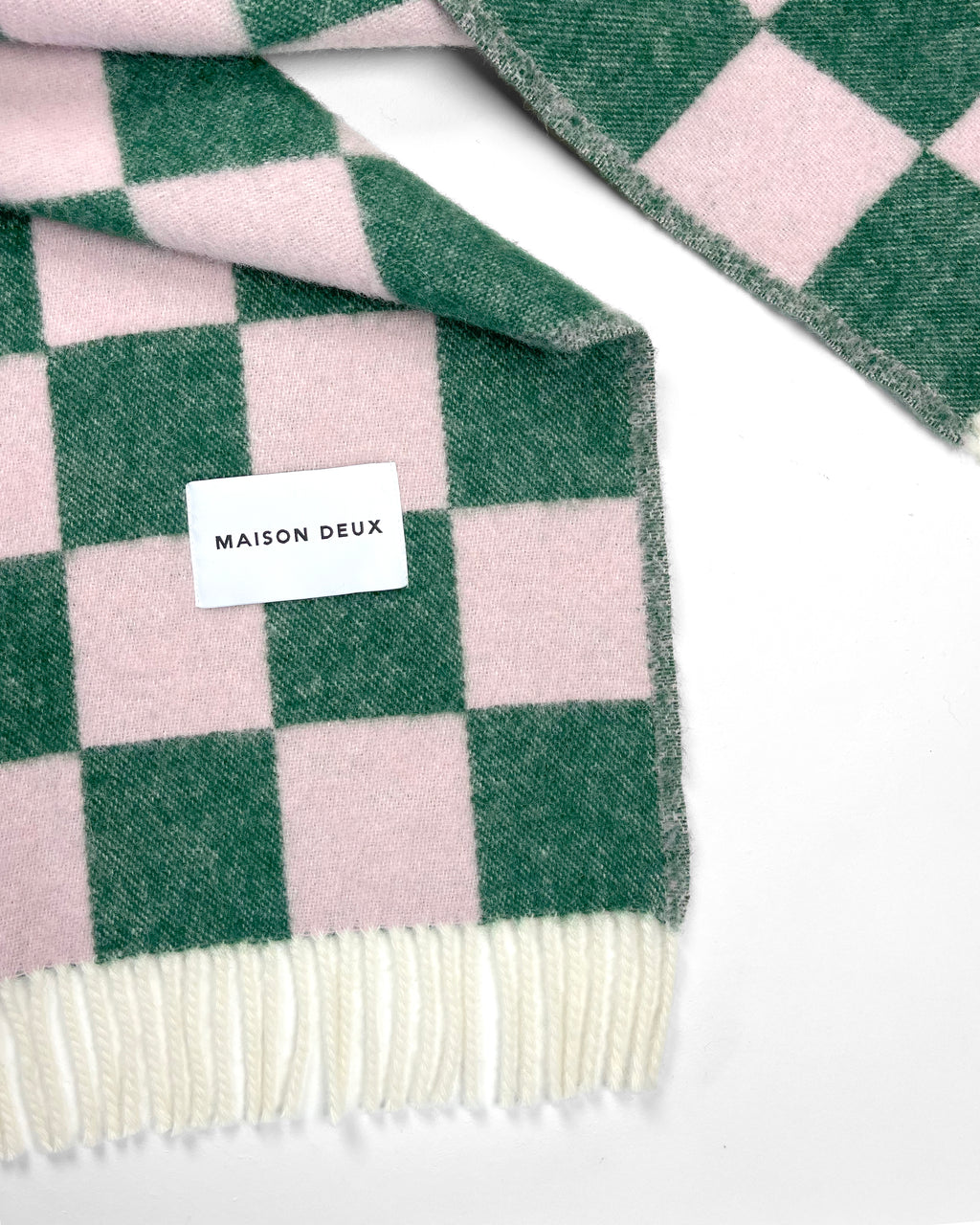 Close-up of green and pink checkerboard wool plaid with fringe

