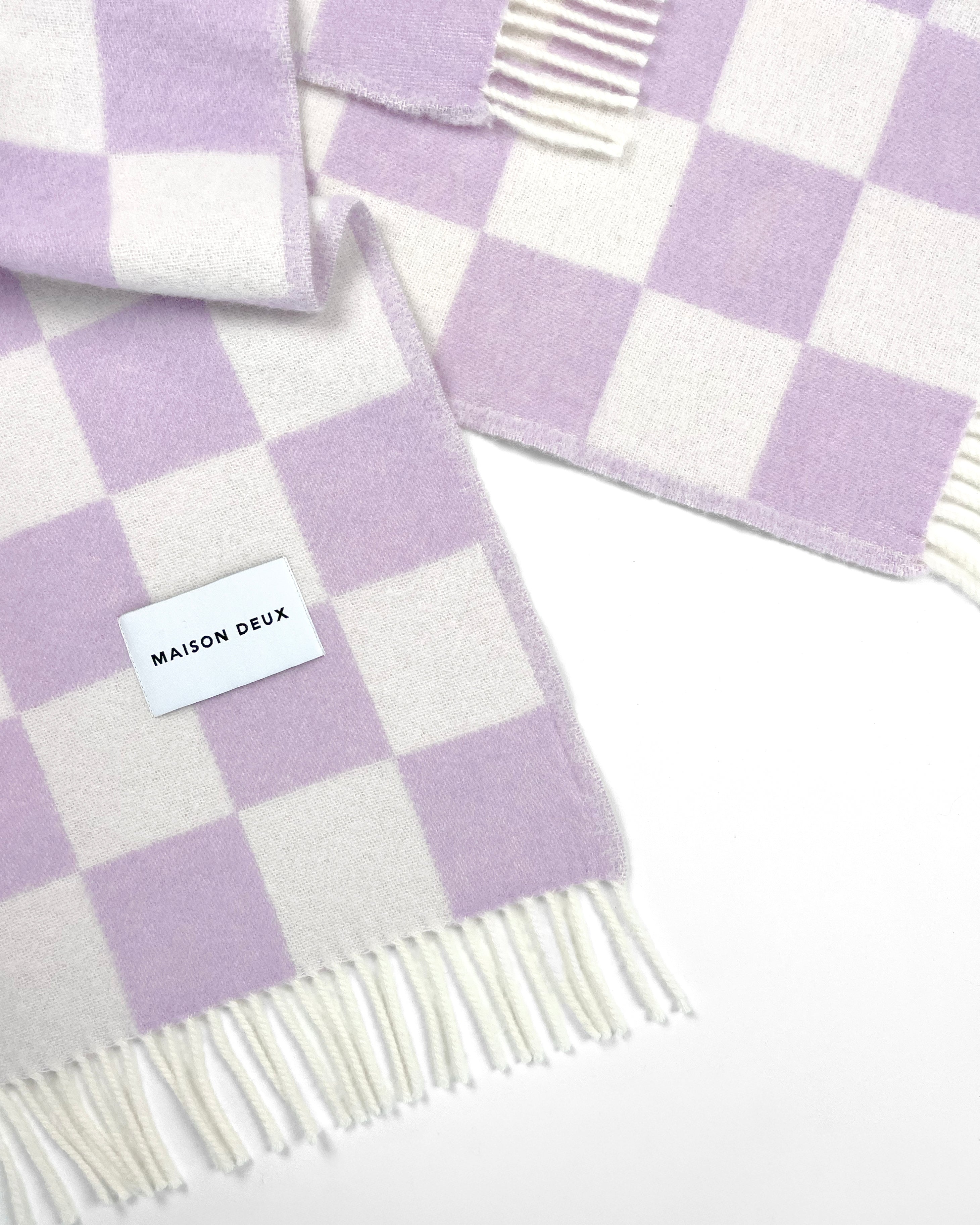 Close-up of twisted lilac and white checkerboard wool plaid with fringe
