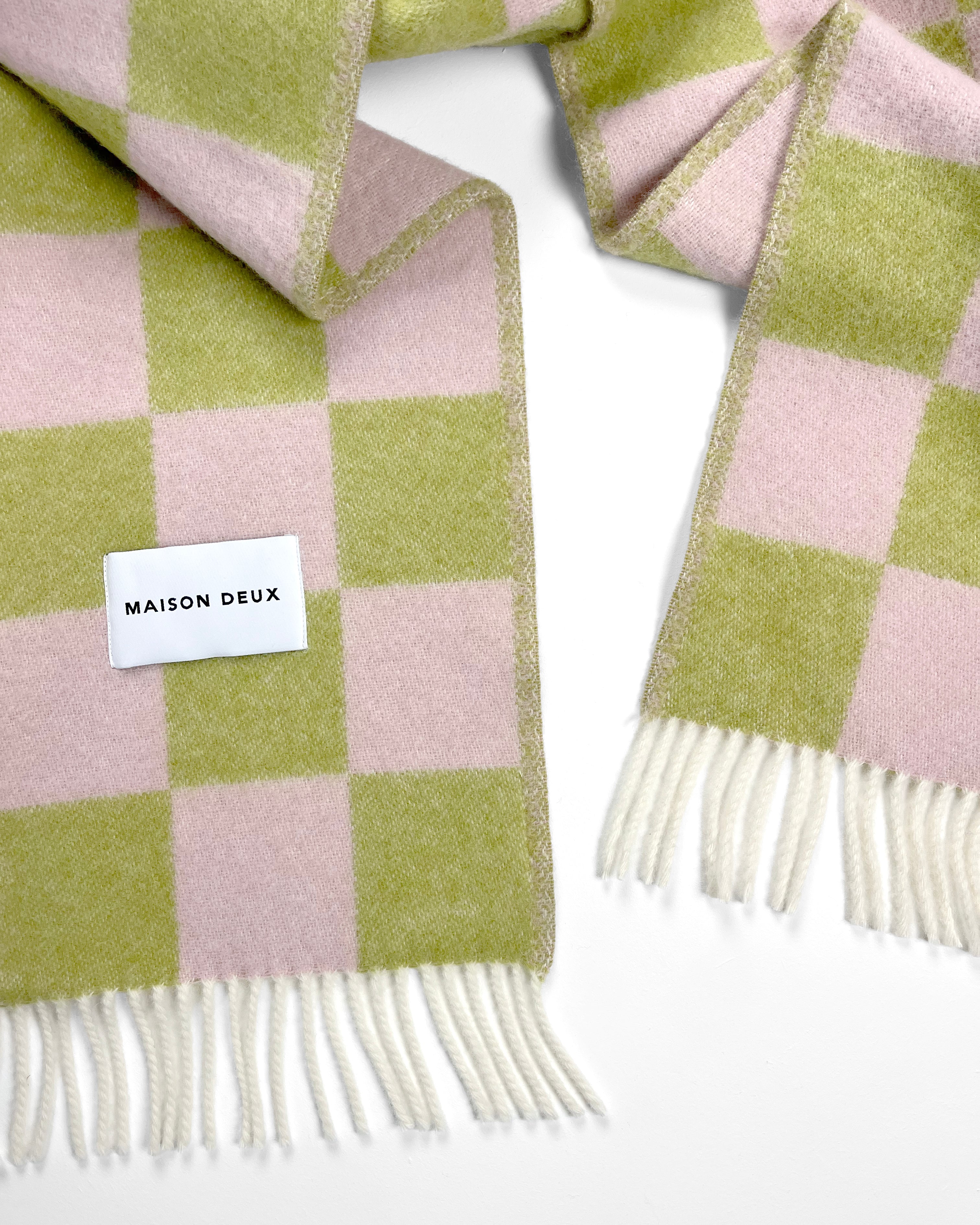 Close-up of twisted lime green and pink checkerboard wool plaid with fringe
