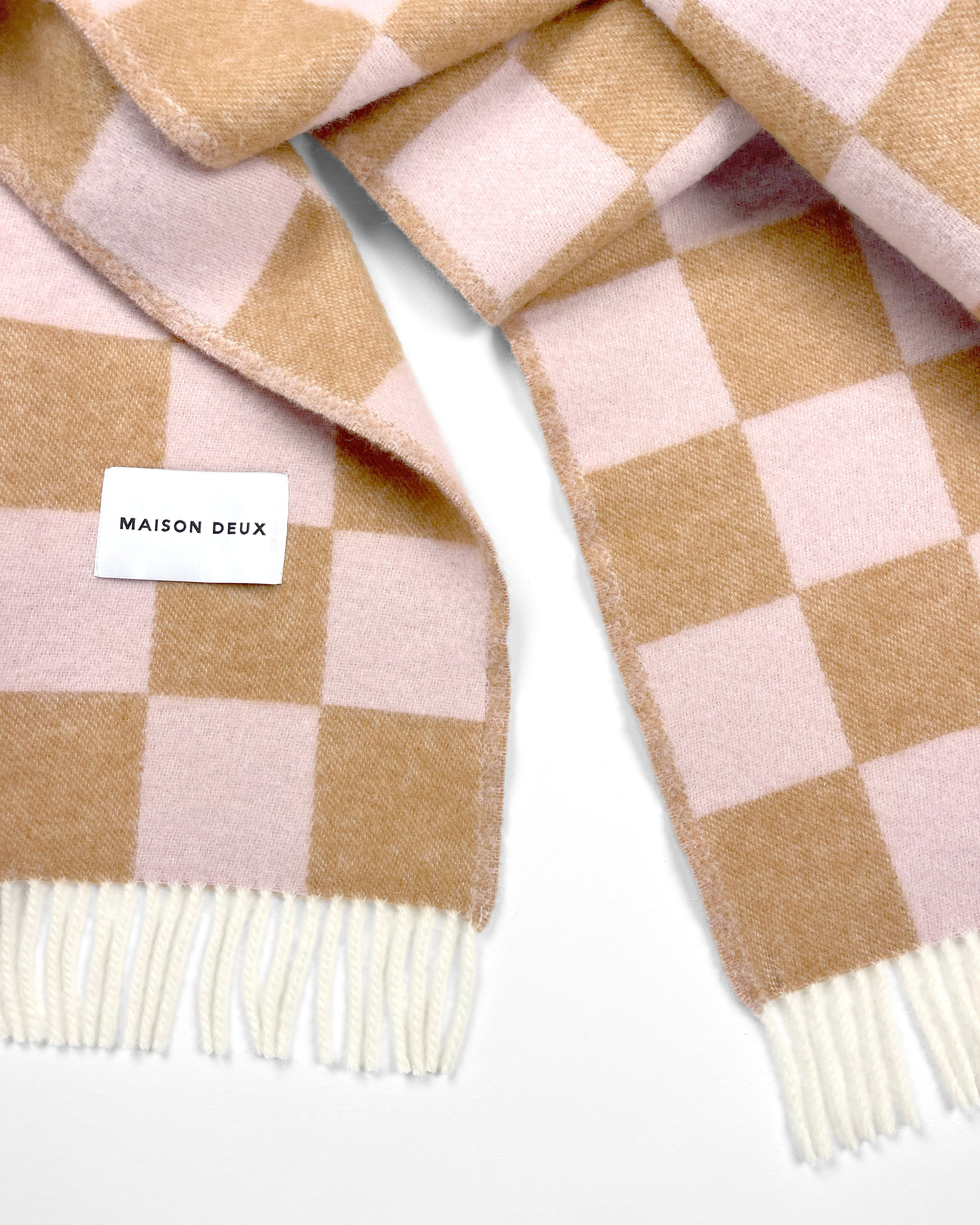 Close-up of twisted terracotta and pink checkerboard wool plaid with fringe
