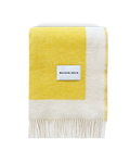 Yellow and white wool blanket folded with fringe detail
