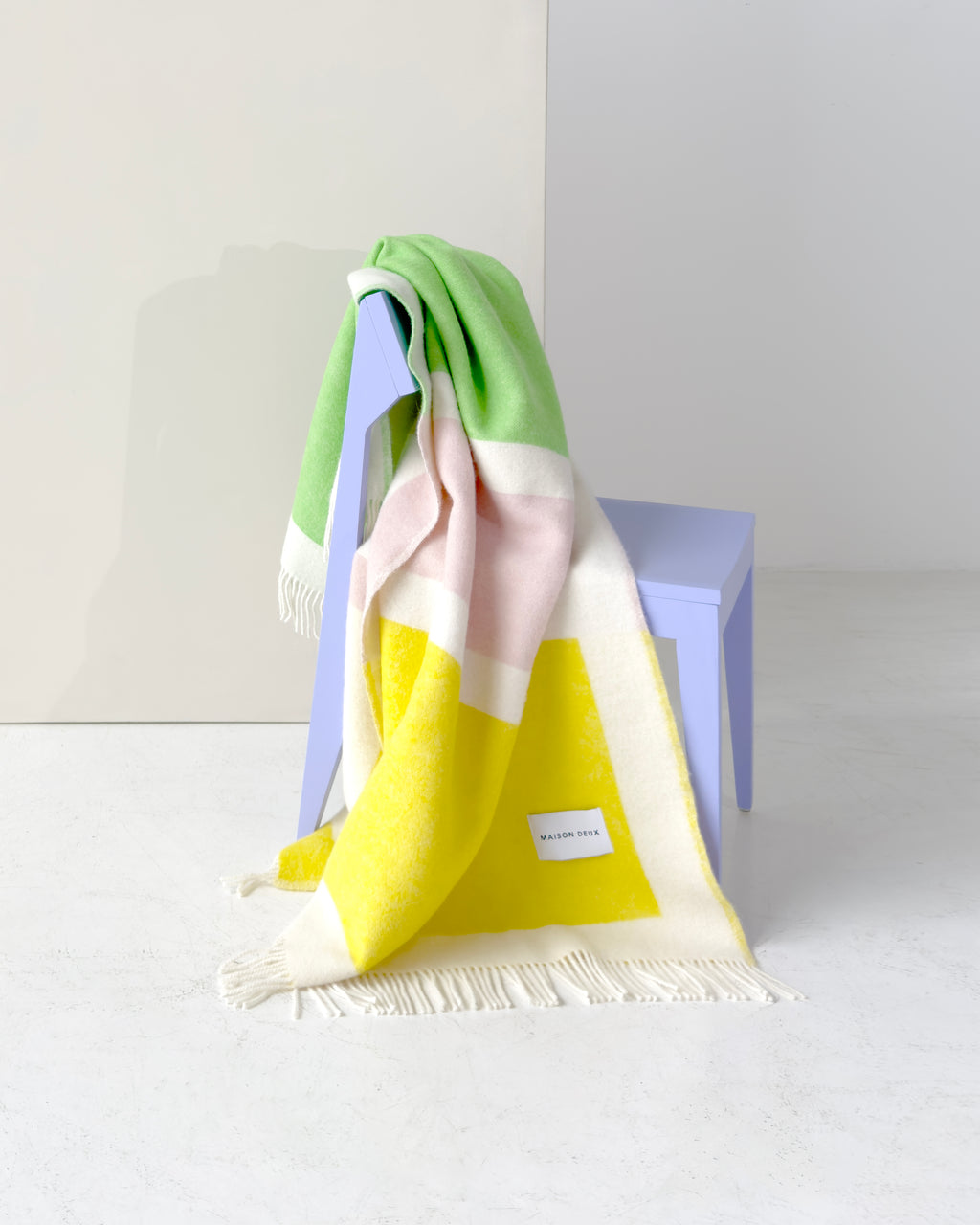 Green, pink, and yellow color block wool blanket draped over chair
