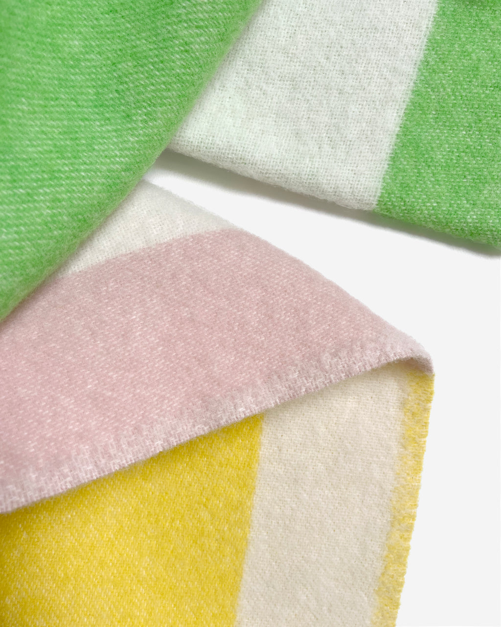 Close-up of folded green, pink, and cream color block wool plaid
