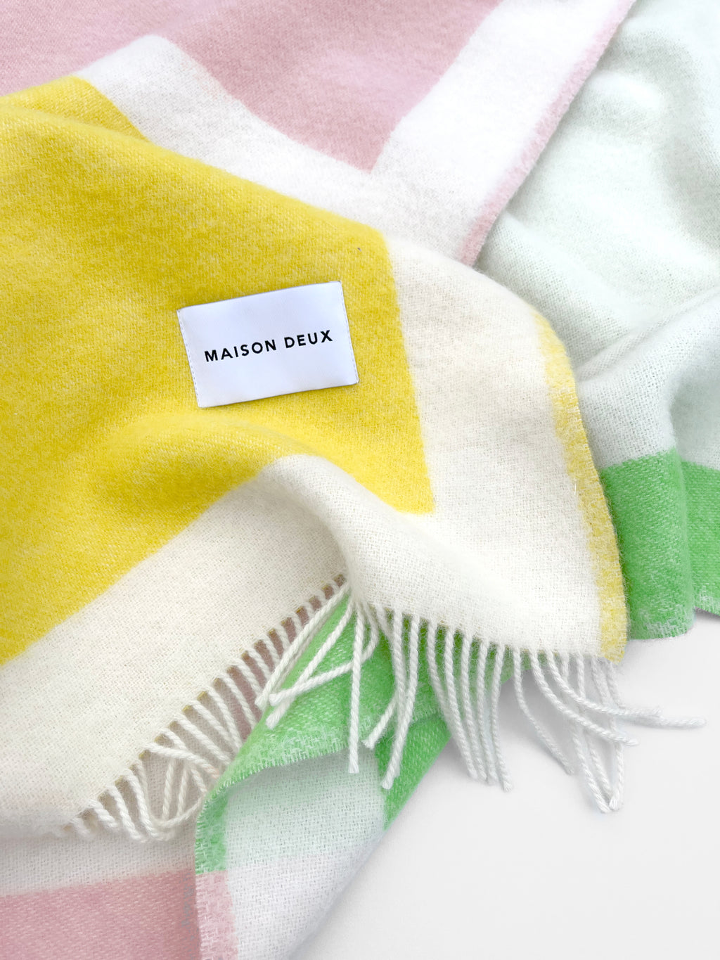 Close-up of yellow, green, and white color block wool throw with fringe
