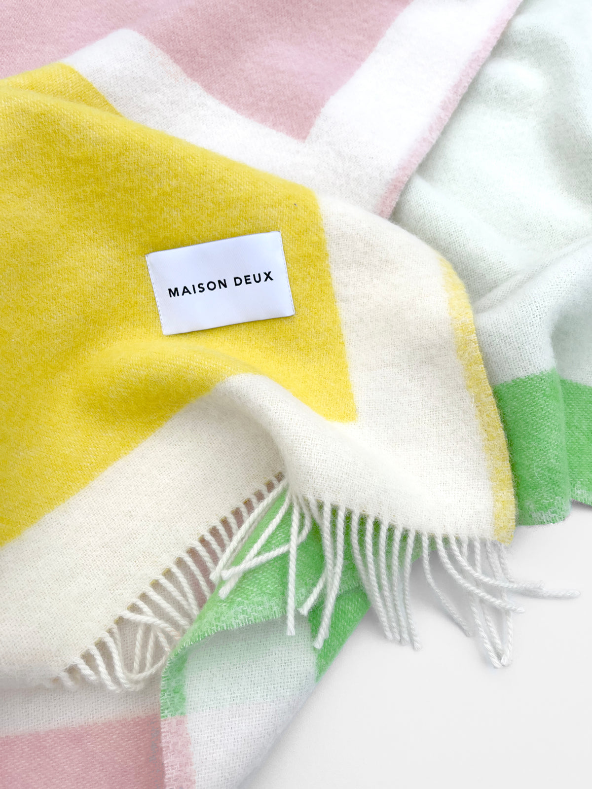 Close-up of yellow, green, and white color block wool throw with fringe
