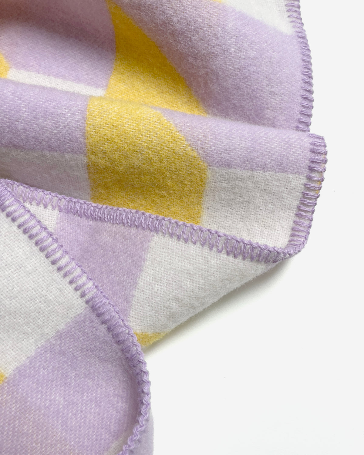 Close-up of folded lilac and yellow geometric wool blanket

