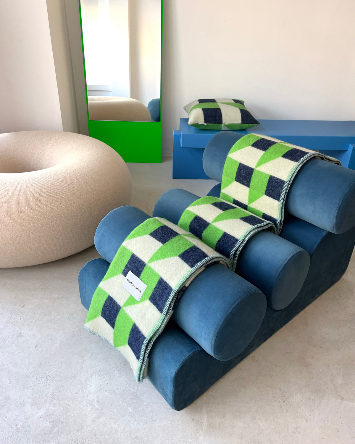 Apple green and navy geometric wool throw draped over seating in styled room
