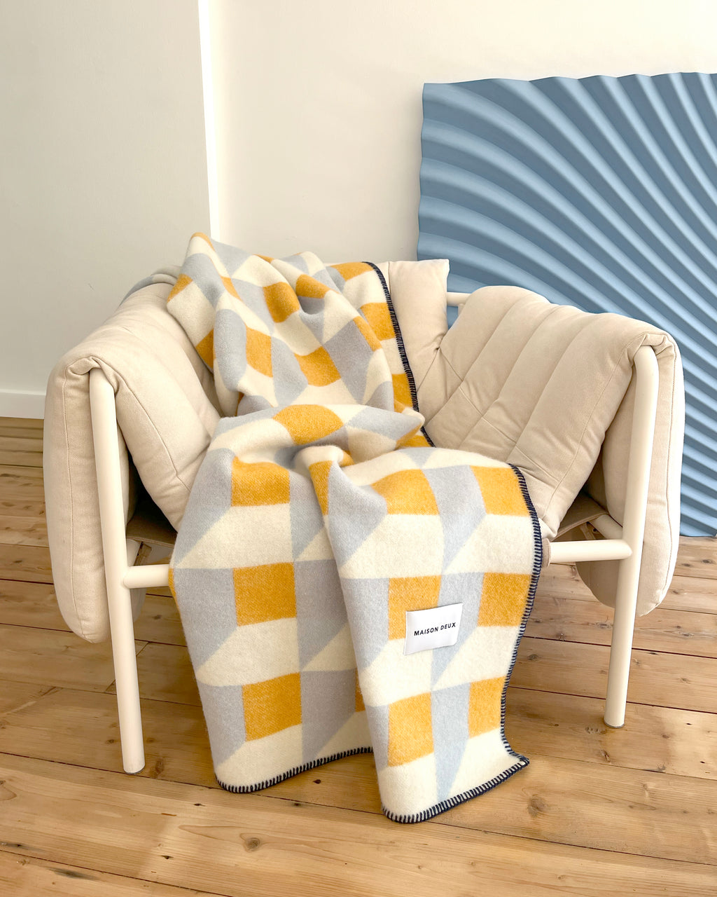 Light blue and honey yellow geometric wool throw draped over armchair in styled room
