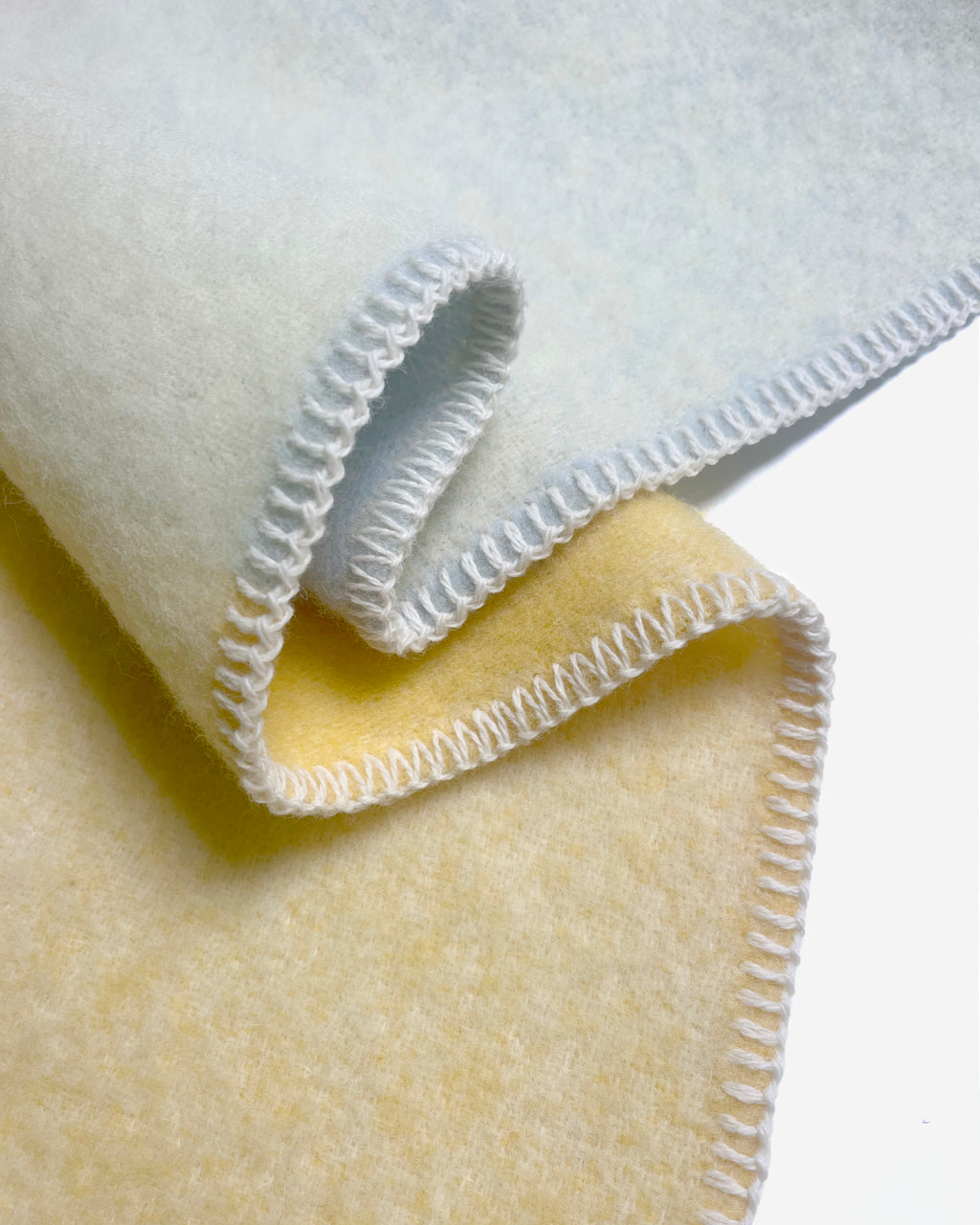 Close-up of folded light blue and butter yellow gradient wool plaid with stitched edge
