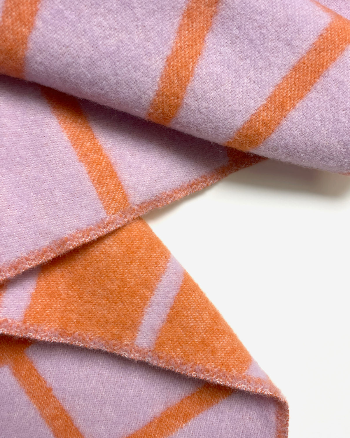 Close-up of folded lilac and orange diagonal striped wool blanket
