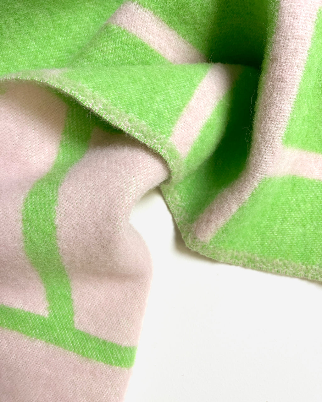 Close-up of folded pink and apple green diagonal striped wool blanket
