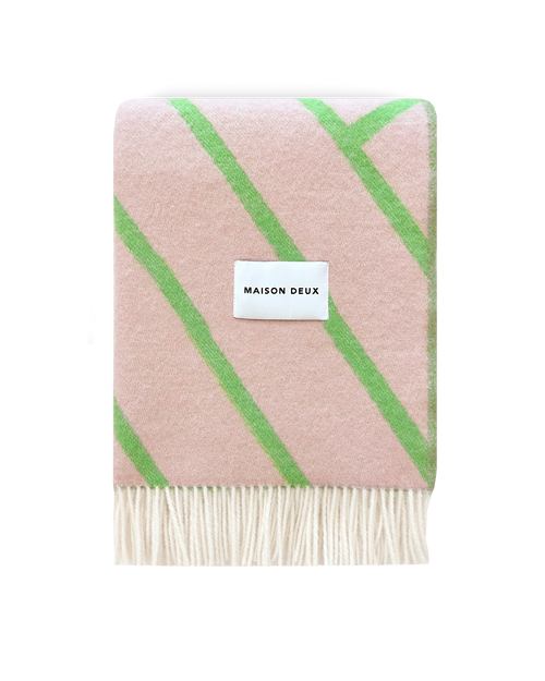 Pink and apple green diagonal striped wool blanket folded with fringe detail
