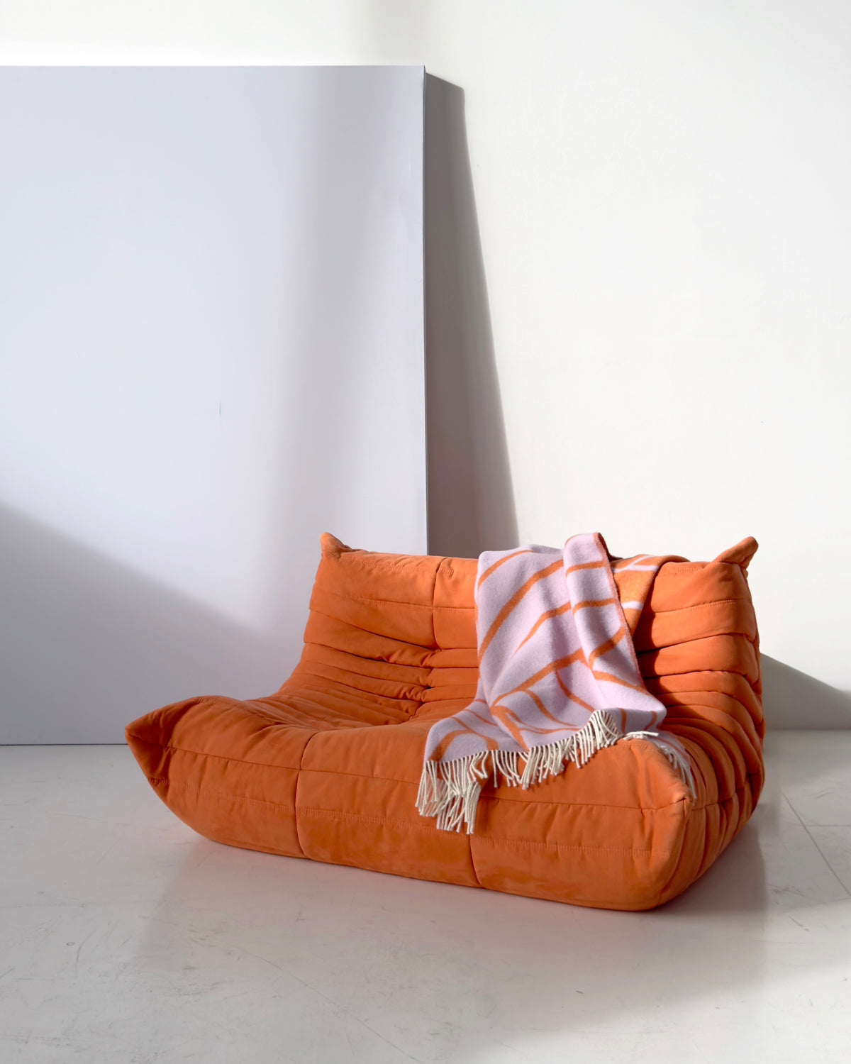 Lilac and orange diagonal striped wool plaid draped over sofa
