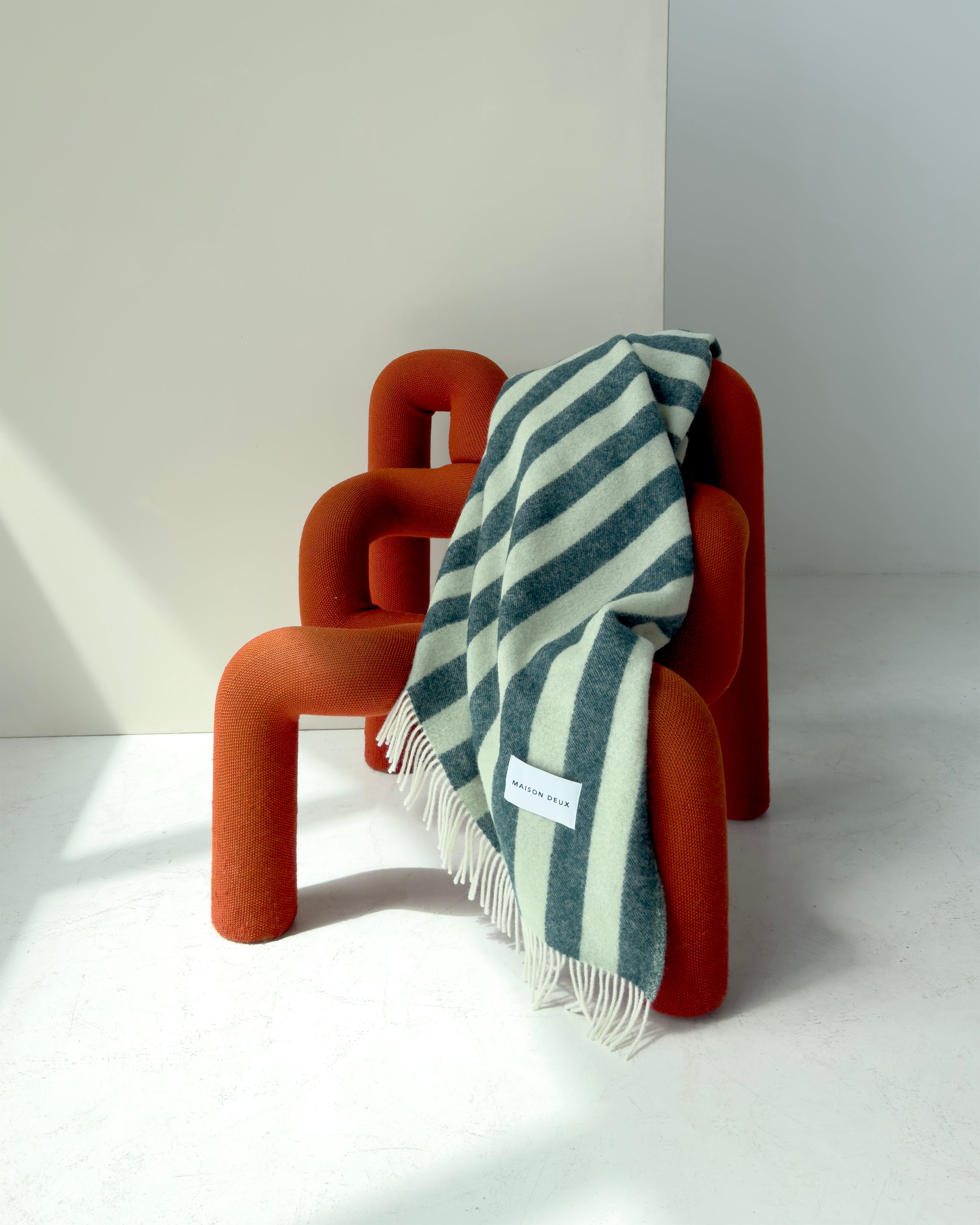 Dark green and sage striped wool plaid draped over red chair
