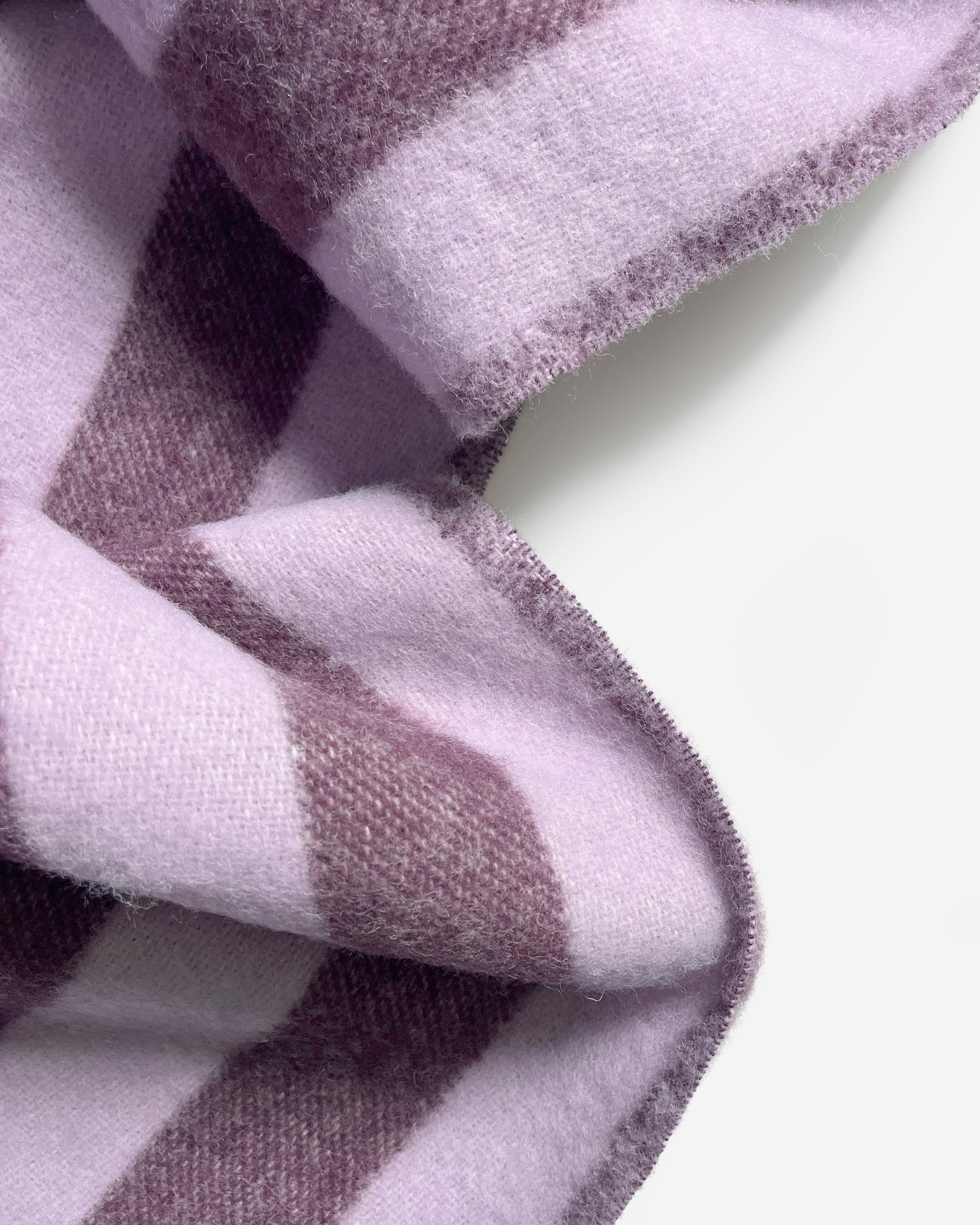 Close-up of folded lilac and aubergine striped wool blanket
