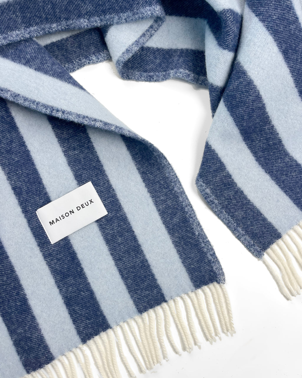 Close-up of navy and light blue striped wool plaid with fringe
