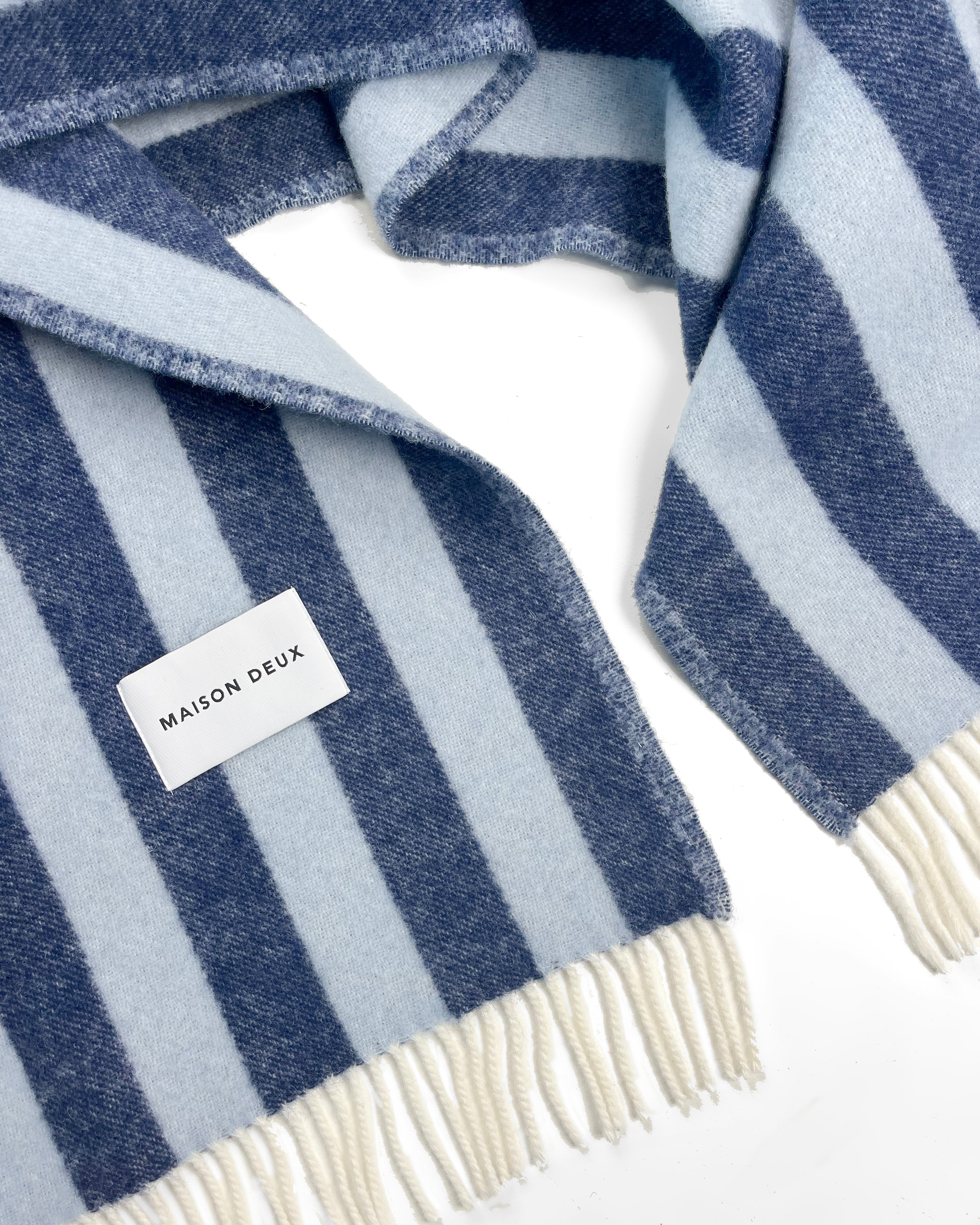 Close-up of navy and light blue striped wool plaid with fringe
