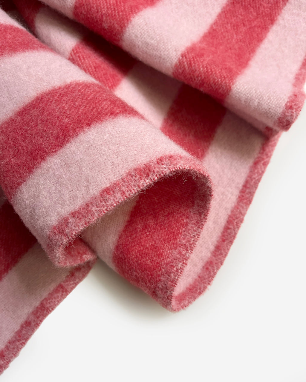 Close-up of folded pink and cherry red striped wool plaid

