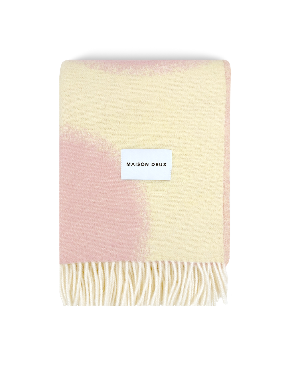 Butter yellow and pink wool blanket folded with fringe detail

