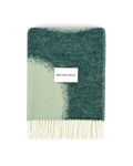 Dark green and sage wool blanket folded with fringe detail
