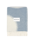 Denim blue and white wool blanket folded with fringe detail
