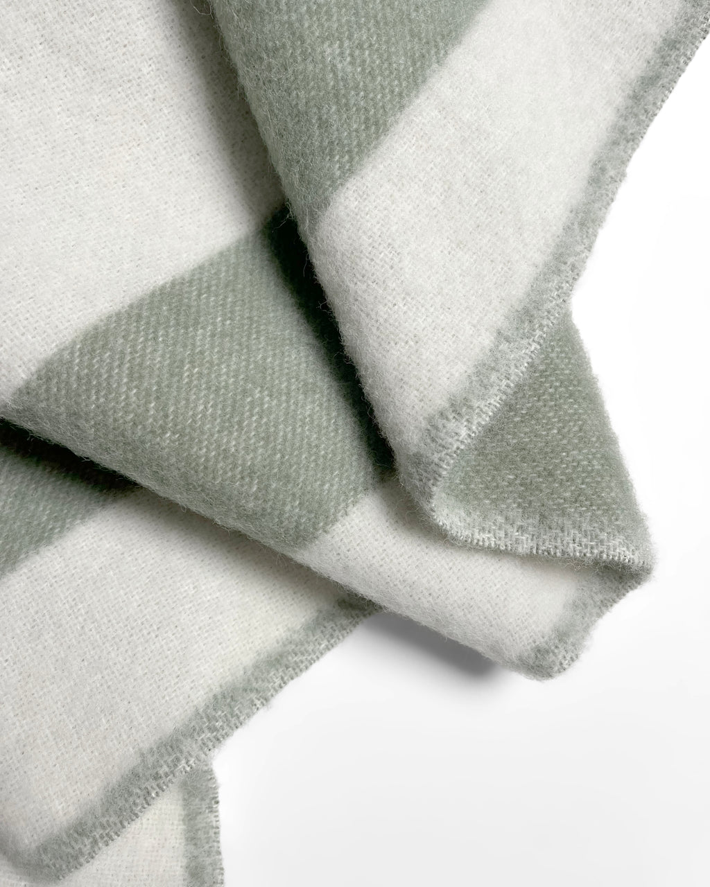 Close-up of folded sage green and white striped wool blanket
