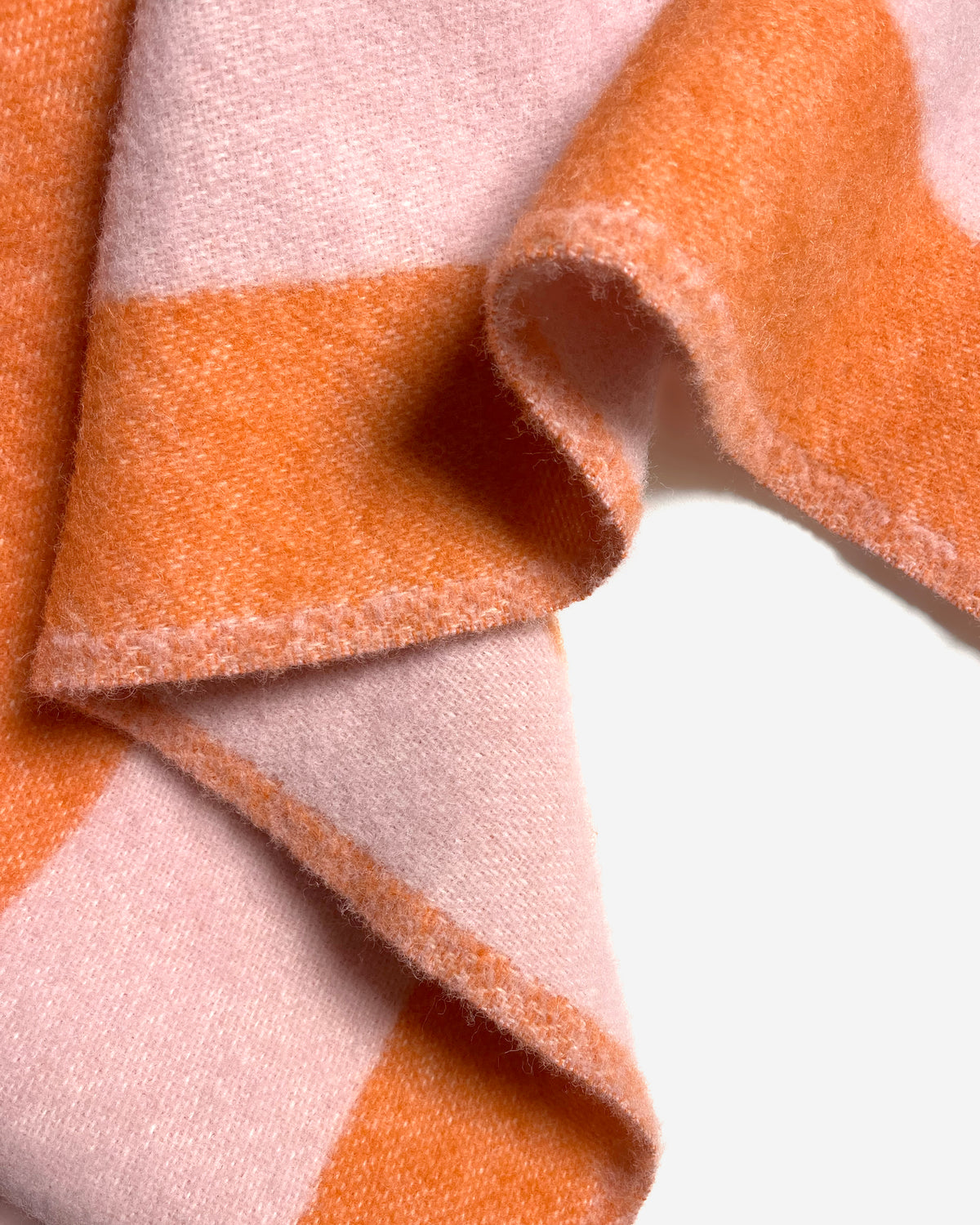 Close-up of folded pink and carrot orange striped wool plaid
