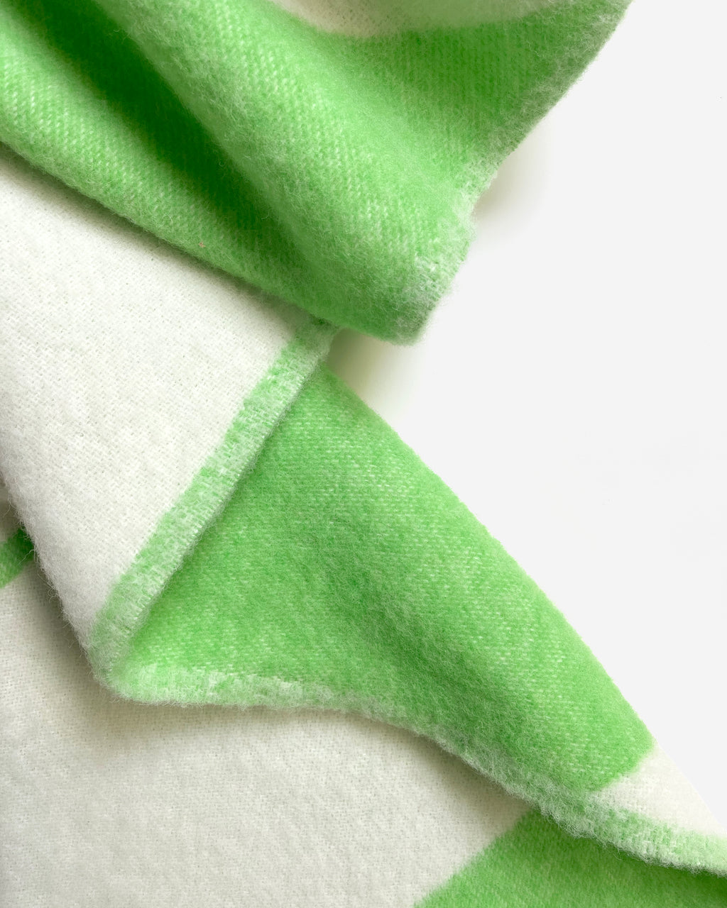 Close-up of folded apple green and white swirl wool blanket
