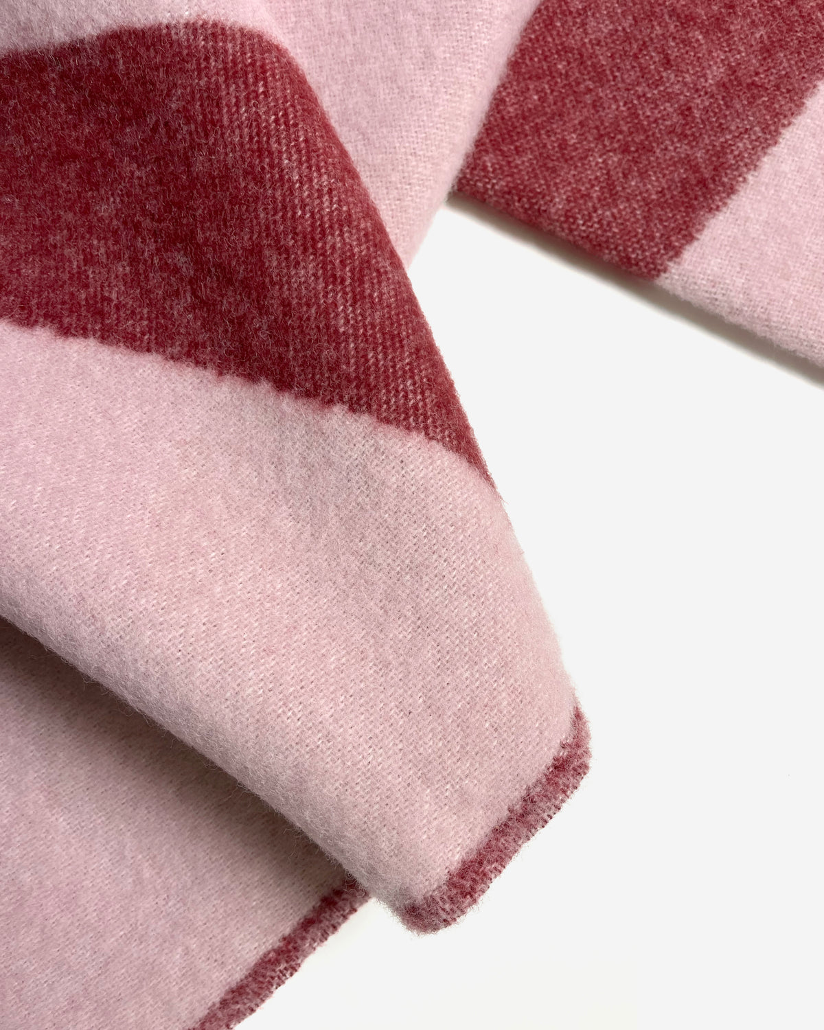 Close-up of folded pink and bordeaux swirl wool blanket
