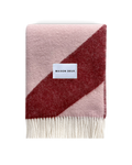 Pink and bordeaux swirl wool blanket folded with fringe detail